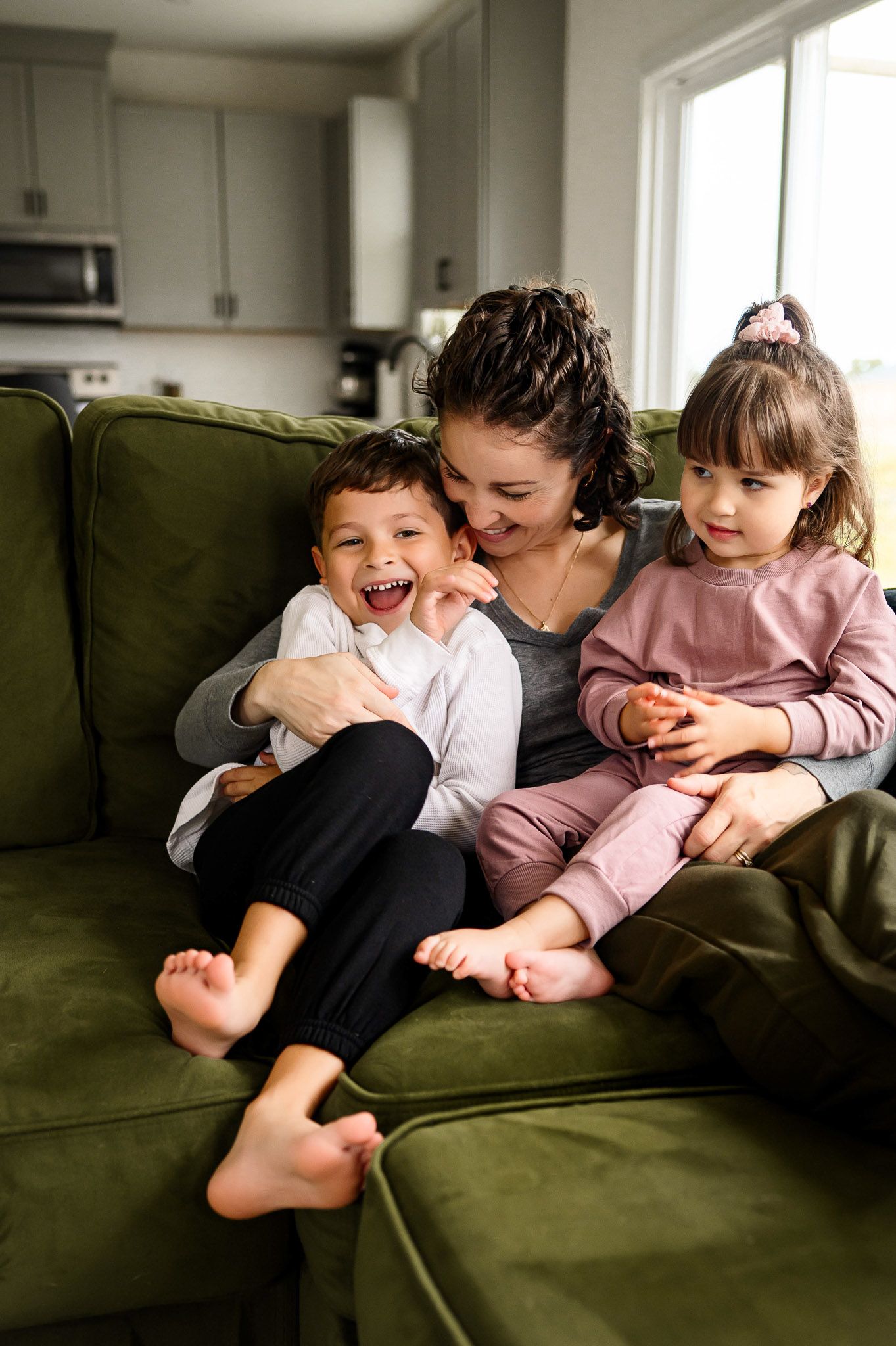 Mother cuddling her children on the couch during a cozy in-home family photography session in Durham North Carolina