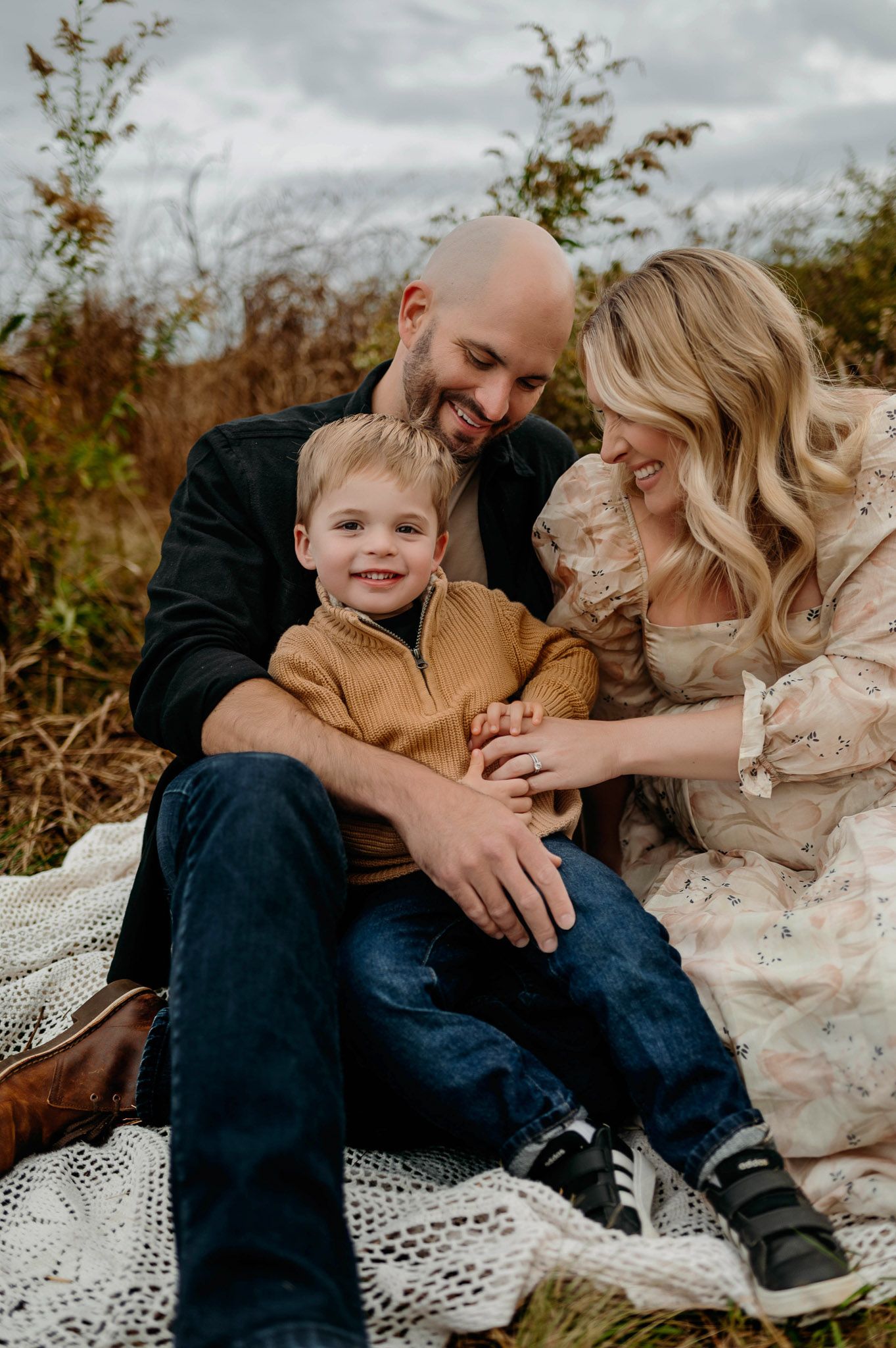 Family maternity photography session with parents and toddler sitting together outdoors in Durham NC