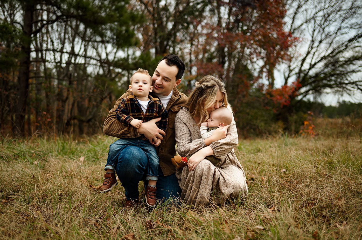 Parents sitting with their toddler and baby during an outdoor fall family photography session in Raleigh NC