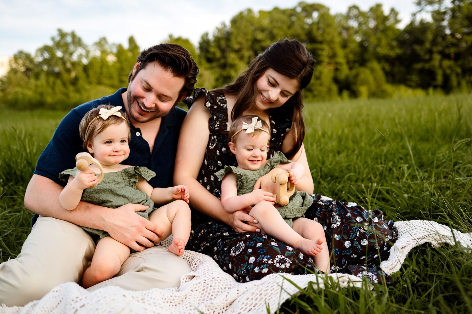 Parents sitting outdoors with their twin babies during a relaxed family photography session in Raleigh NC
