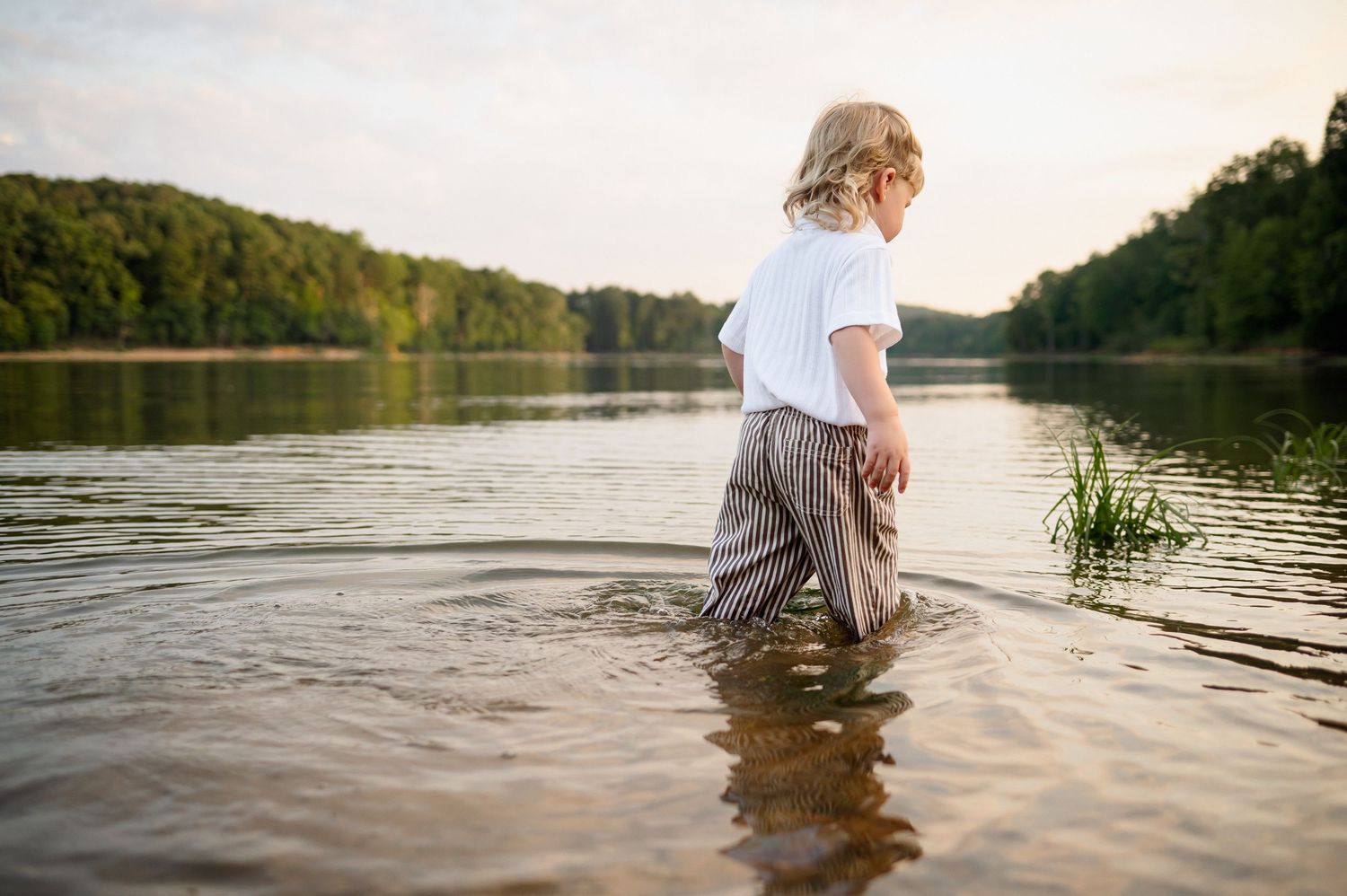 Young child wading in a lake during an outdoor lifestyle family photography session in Raleigh, NC