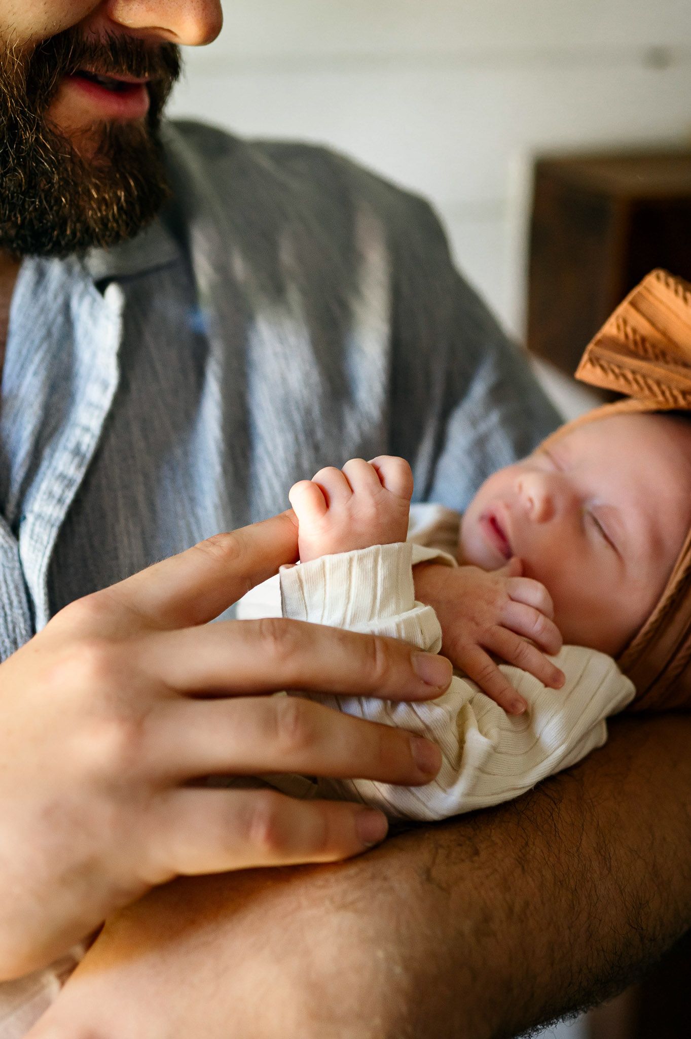 Father holding his sleeping newborn baby during a natural light lifestyle newborn photography session in Durham NC