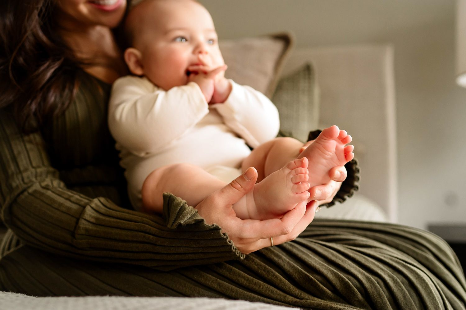 Close-up detail of baby feet held in a mother's hands during a lifestyle family photography session in Raleigh NC
