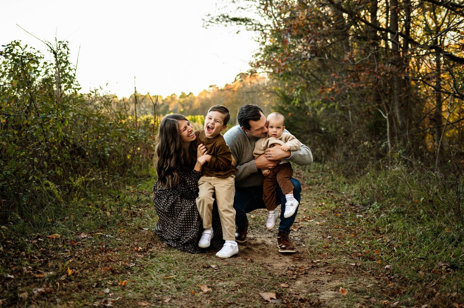 Family shares a joyful and candid moment together on a trail surrounded by fall foliage during photoshoot with Emma Branch Photogaphy