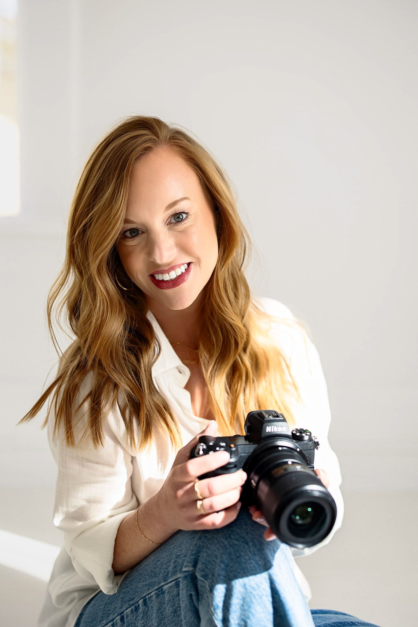 Raleigh family photographer Emma smiling while holding camera in a natural light studio