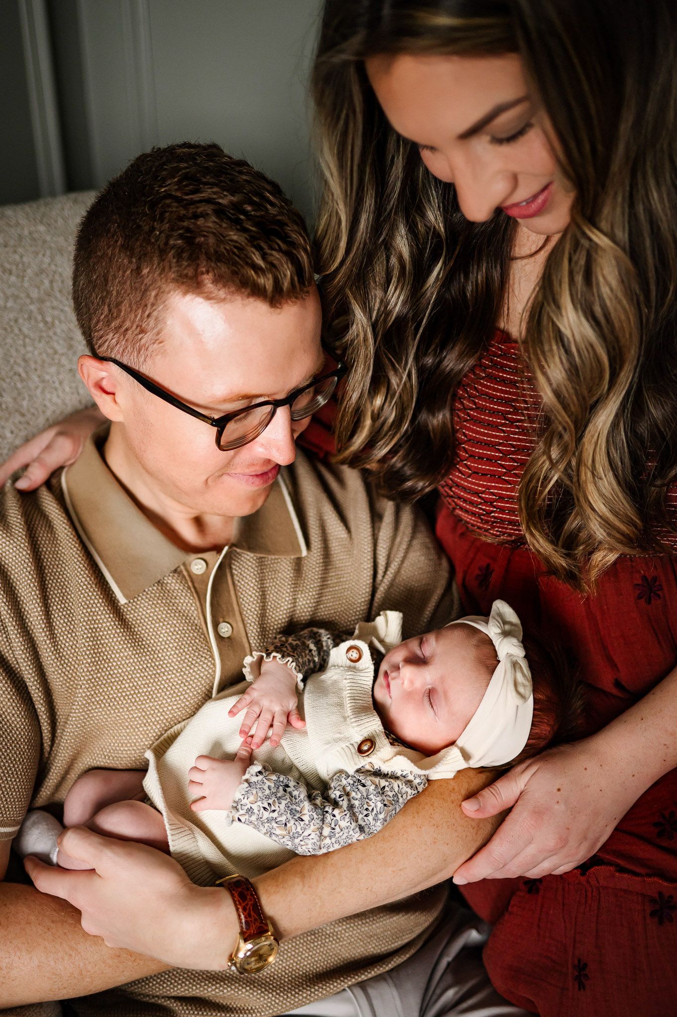 Parents holding and admiring their newborn baby during a cozy in-home lifestyle newborn photography session