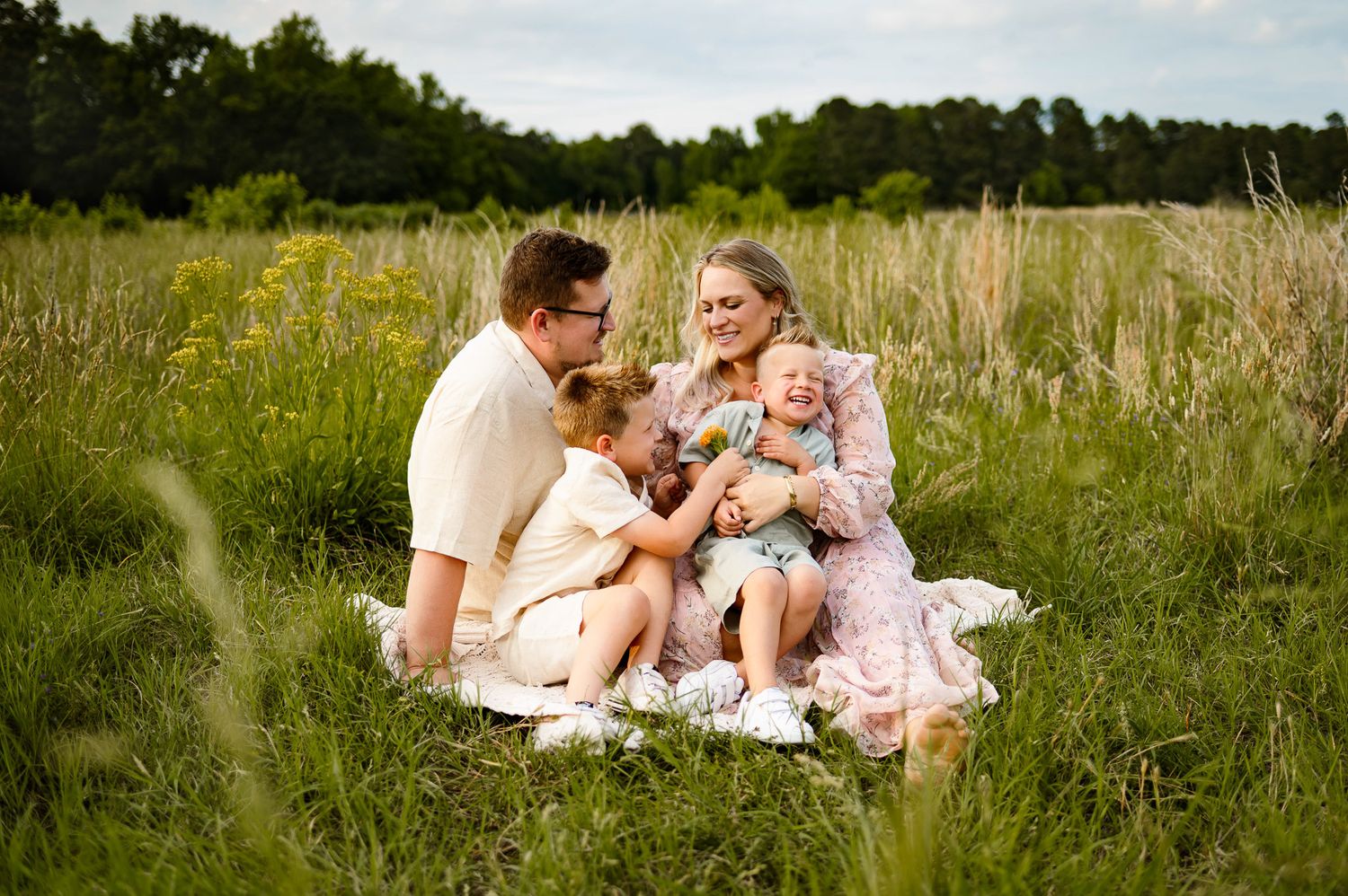 Candid family maternity photo of parents and children laughing together during a Raleigh outdoor maternity photography session