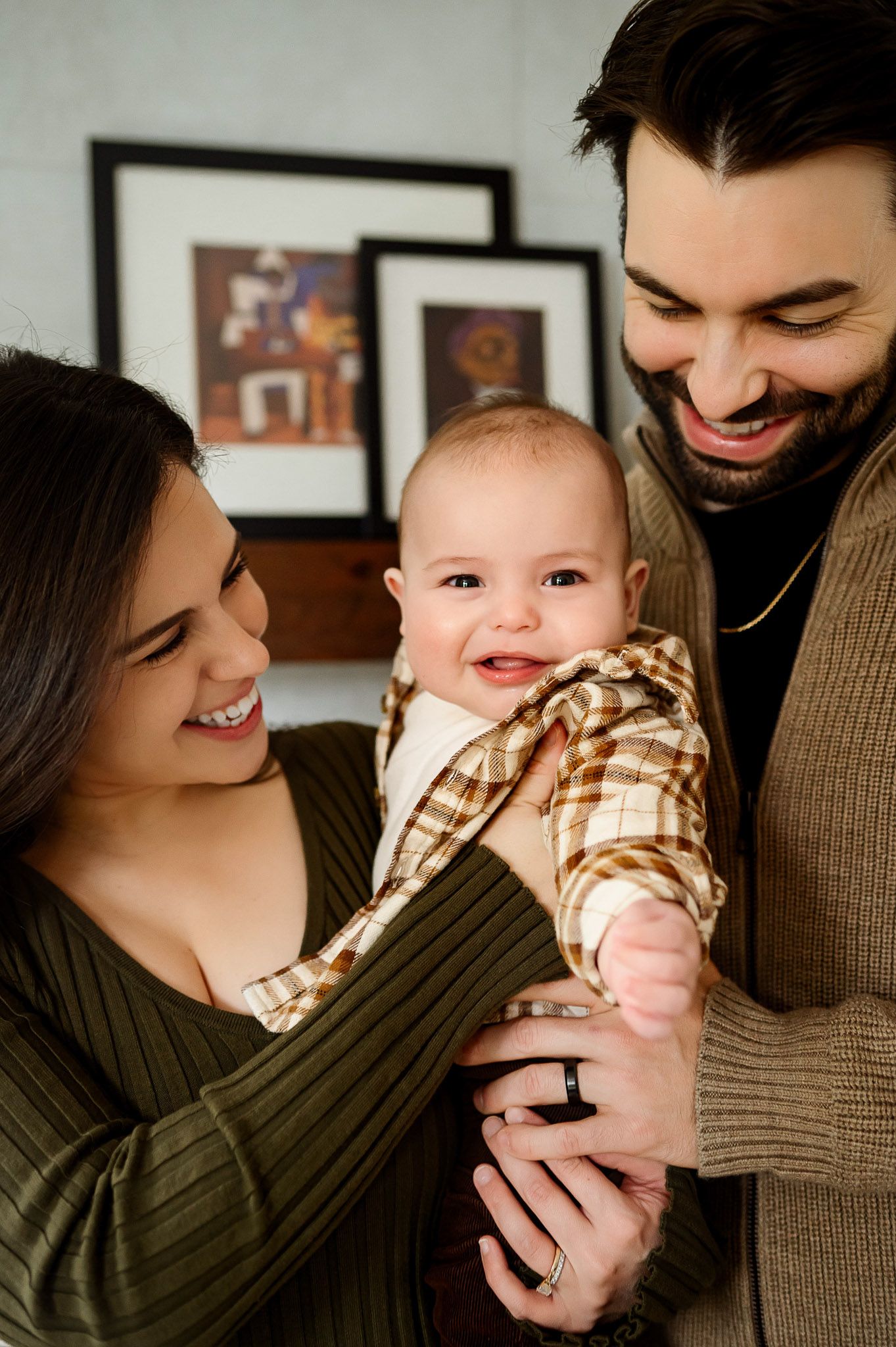 Parents holding their smiling baby during a relaxed lifestyle family photography session at home in Raleigh NC