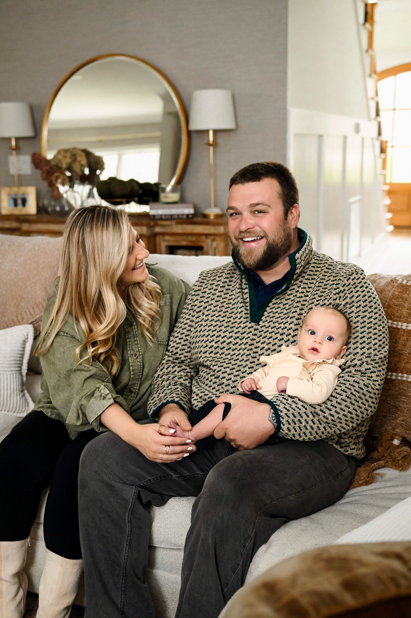 Parents sitting together on the couch with their baby during a natural in-home family photography session