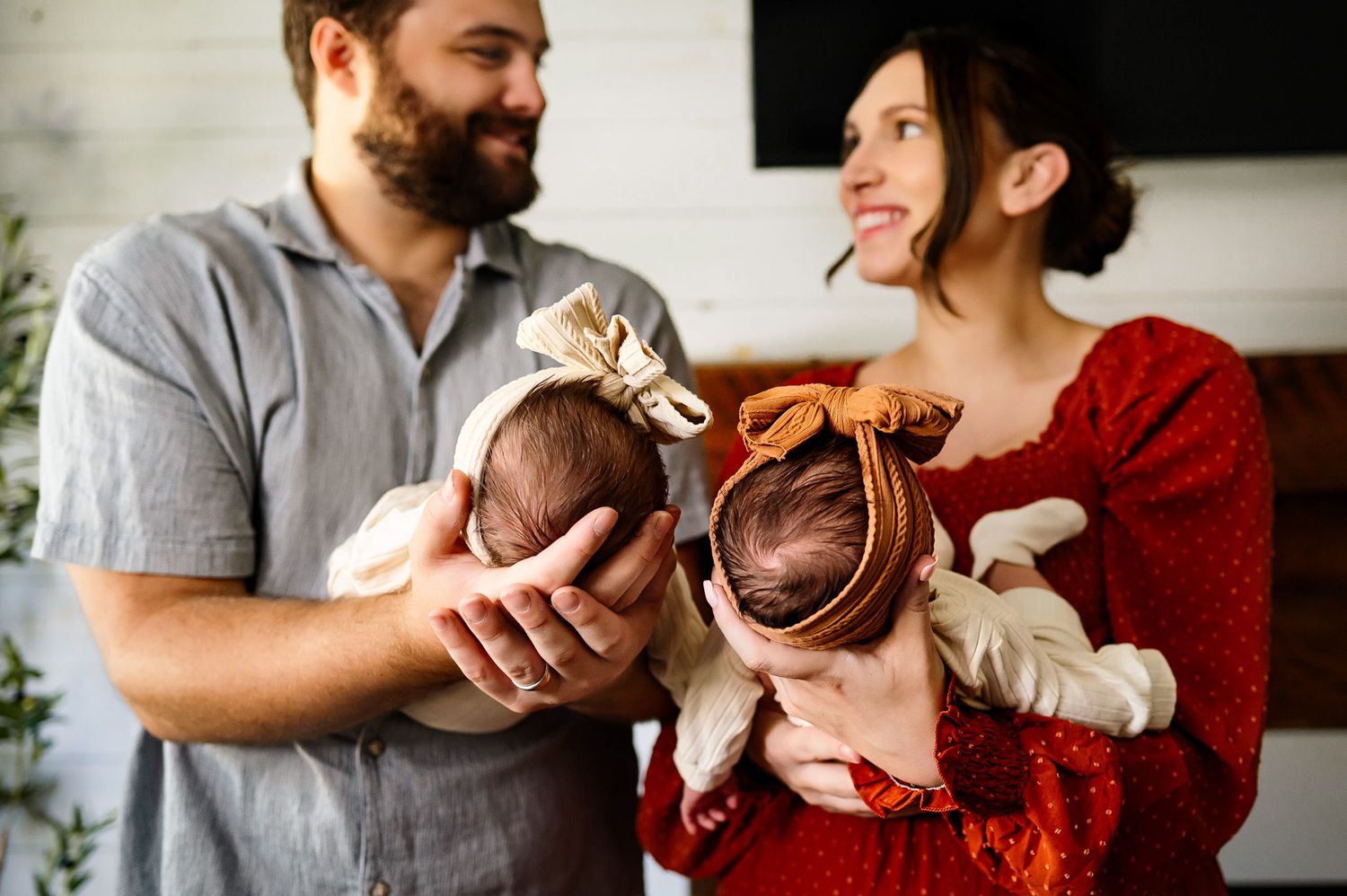 Parents holding newborn twins during cozy in-home newborn photography session in Raleigh NC