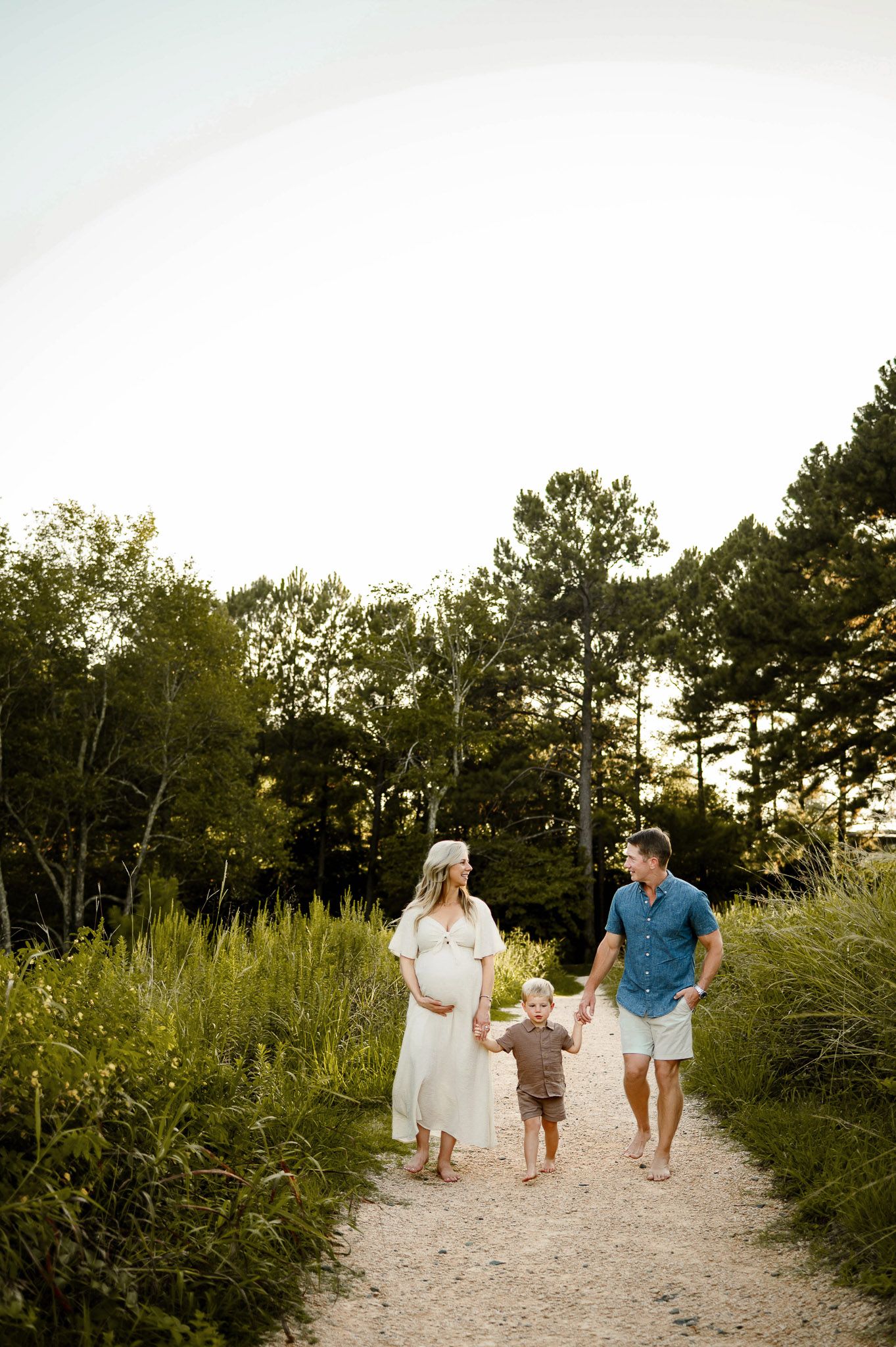 Expecting parents walking with their toddler along a path during a Raleigh maternity photography session