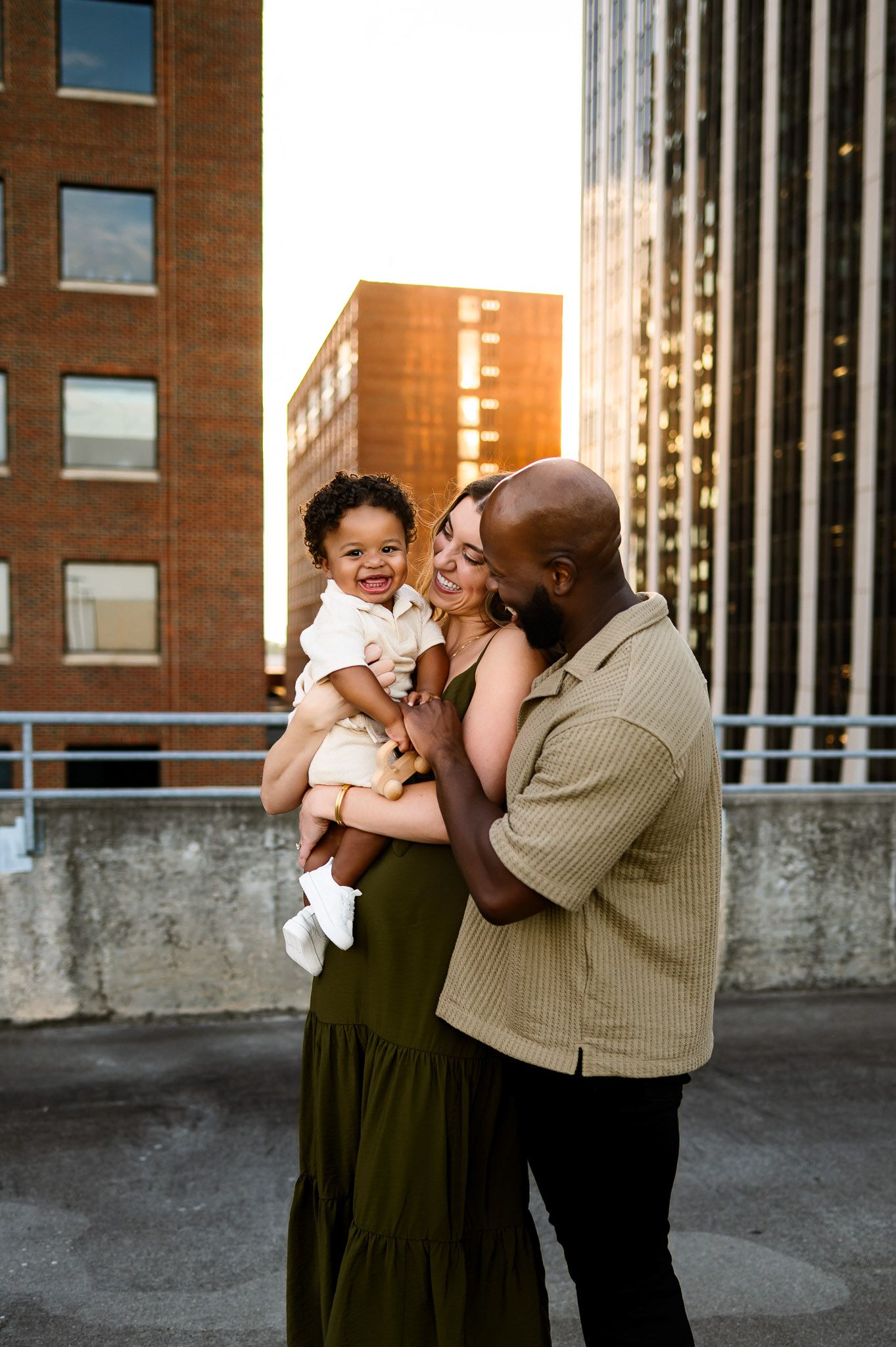 Parents holding their toddler together during a golden hour rooftop family photography session in Raleigh