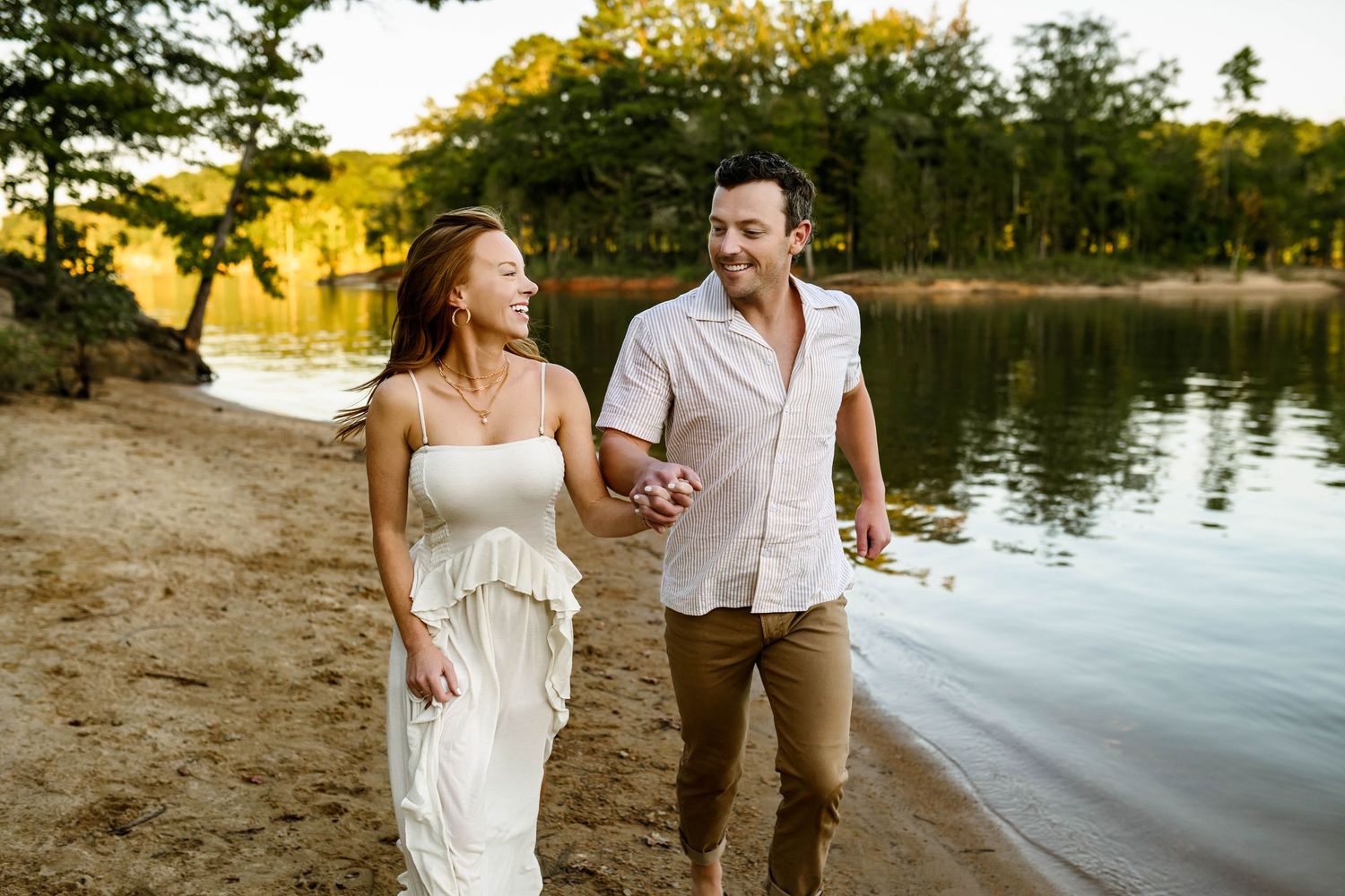 Couple shares romantic and joyful moment by a serene lake during golden hour sunset during family photography session in Raleigh NC