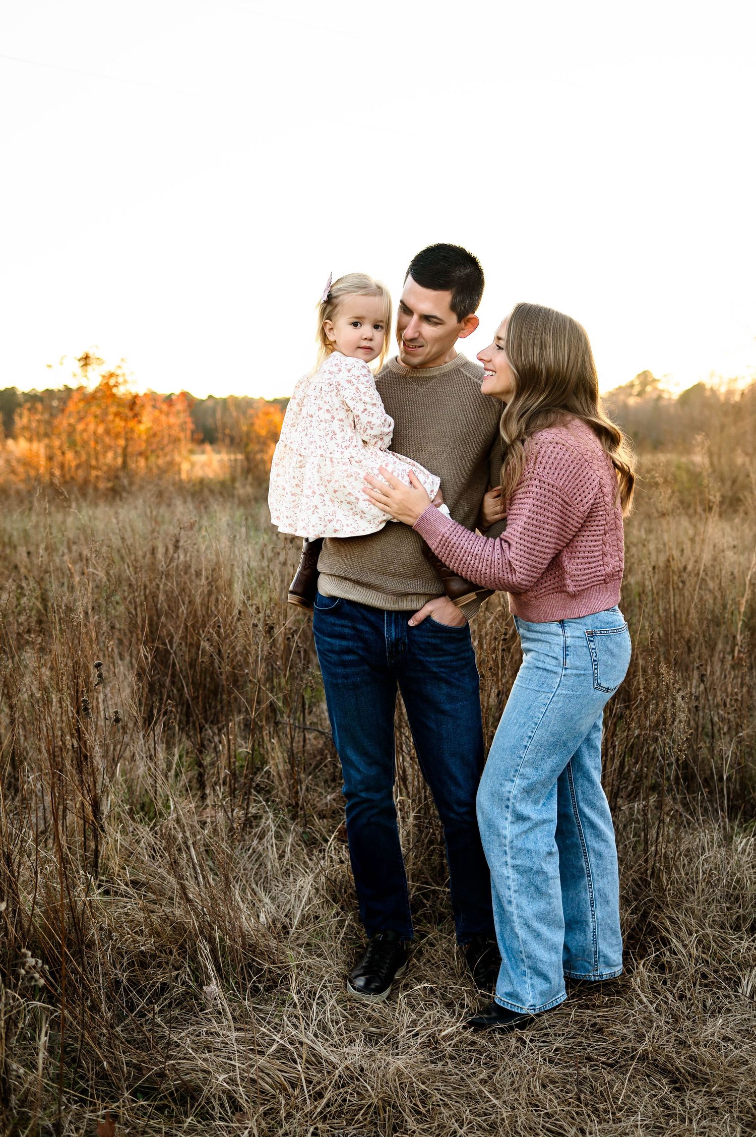 Parents standing with their toddler during a winter outdoor family photography session in Raleigh NC