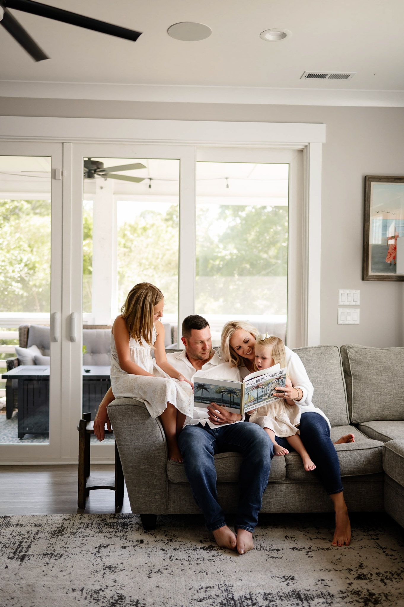 Family reading a children’s book together on the couch during a lifestyle in-home family photography session near Raleigh