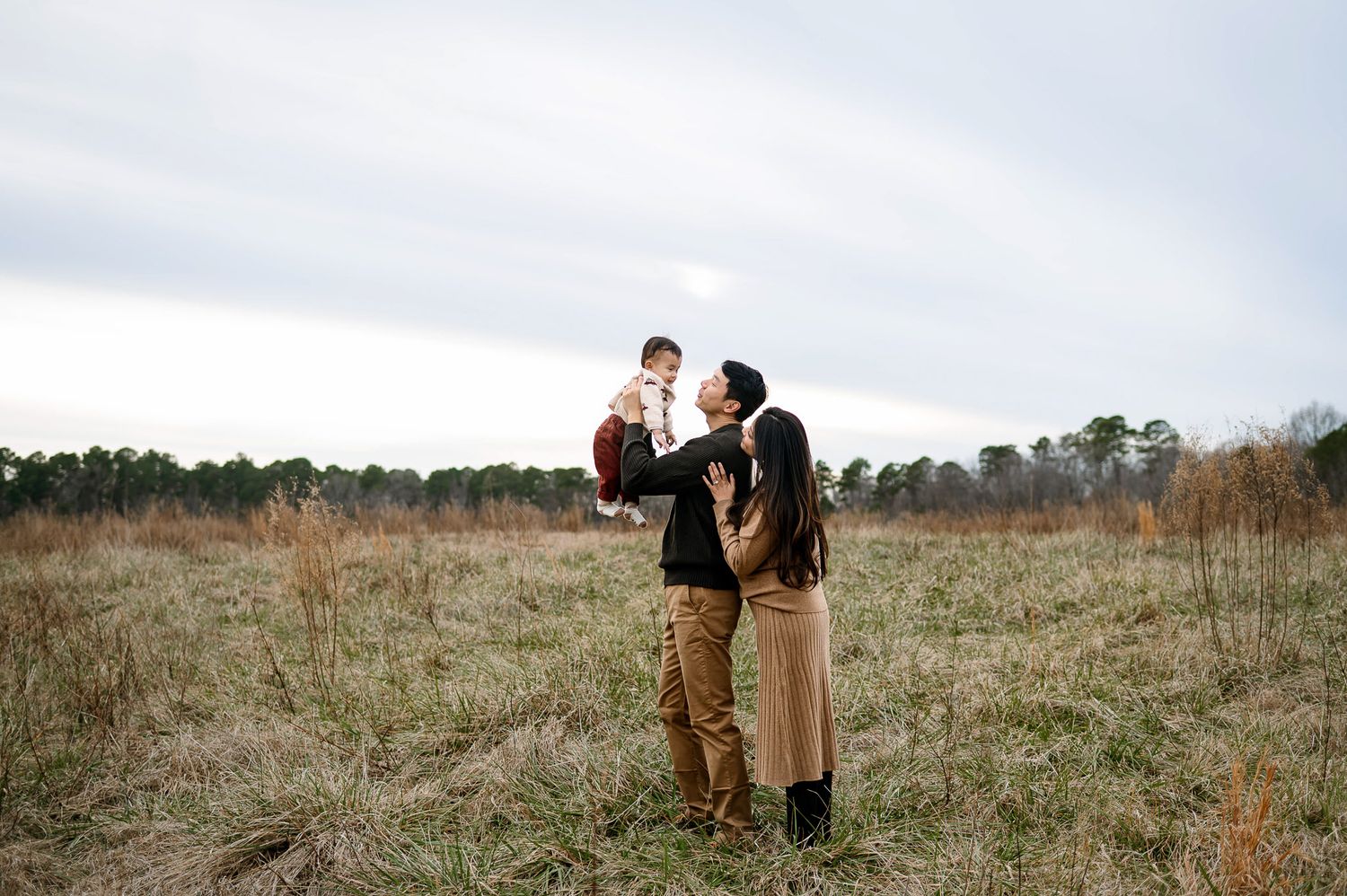 Family standing together in an open field during a Wake Forest family photography session