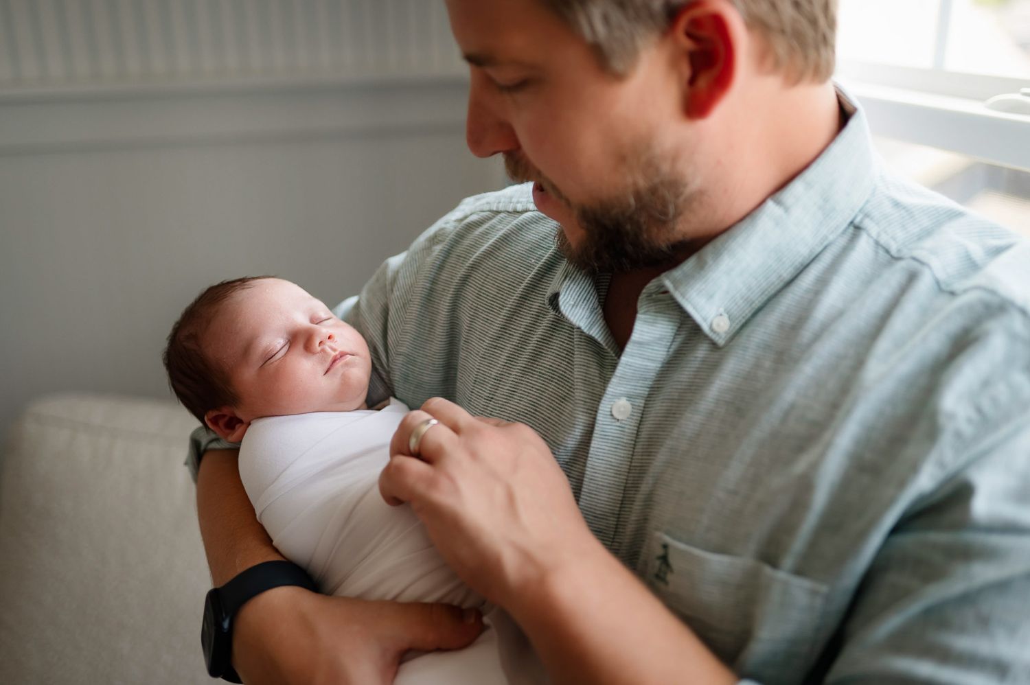 Father holding his sleeping newborn baby during a lifestyle newborn photography session at home in Raleigh NC