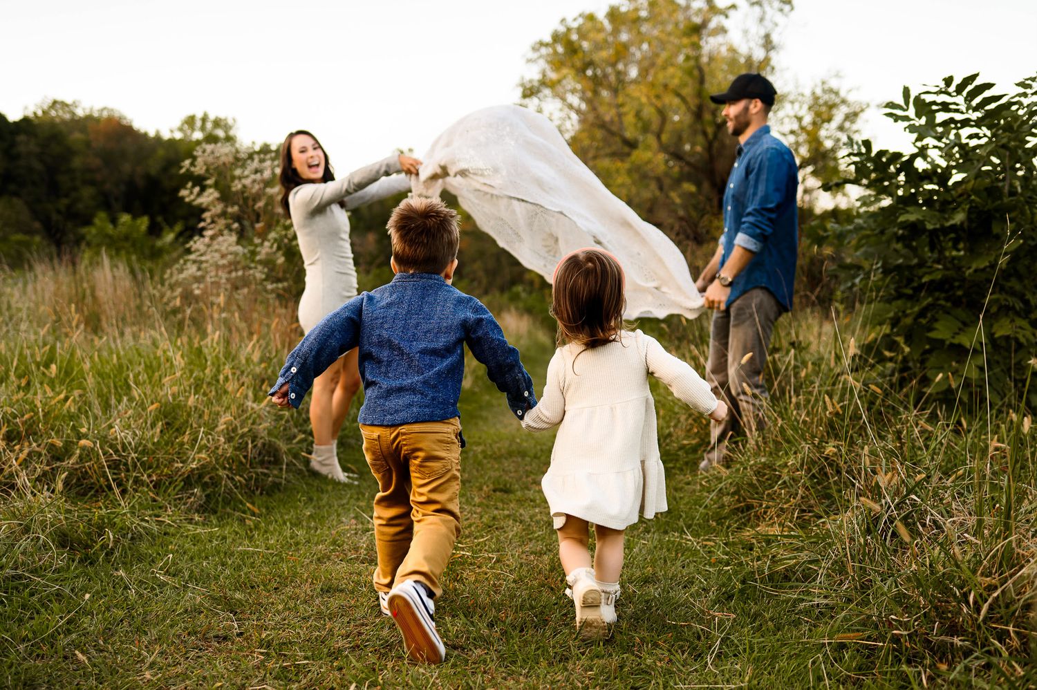 Young children running toward parents during a candid outdoor family photography session in Raleigh NC
