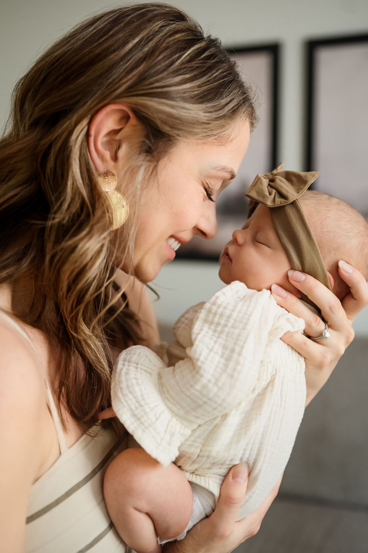 Raleigh newborn photographer captures intimate photo of mother holding baby close while smiling with closed eyes