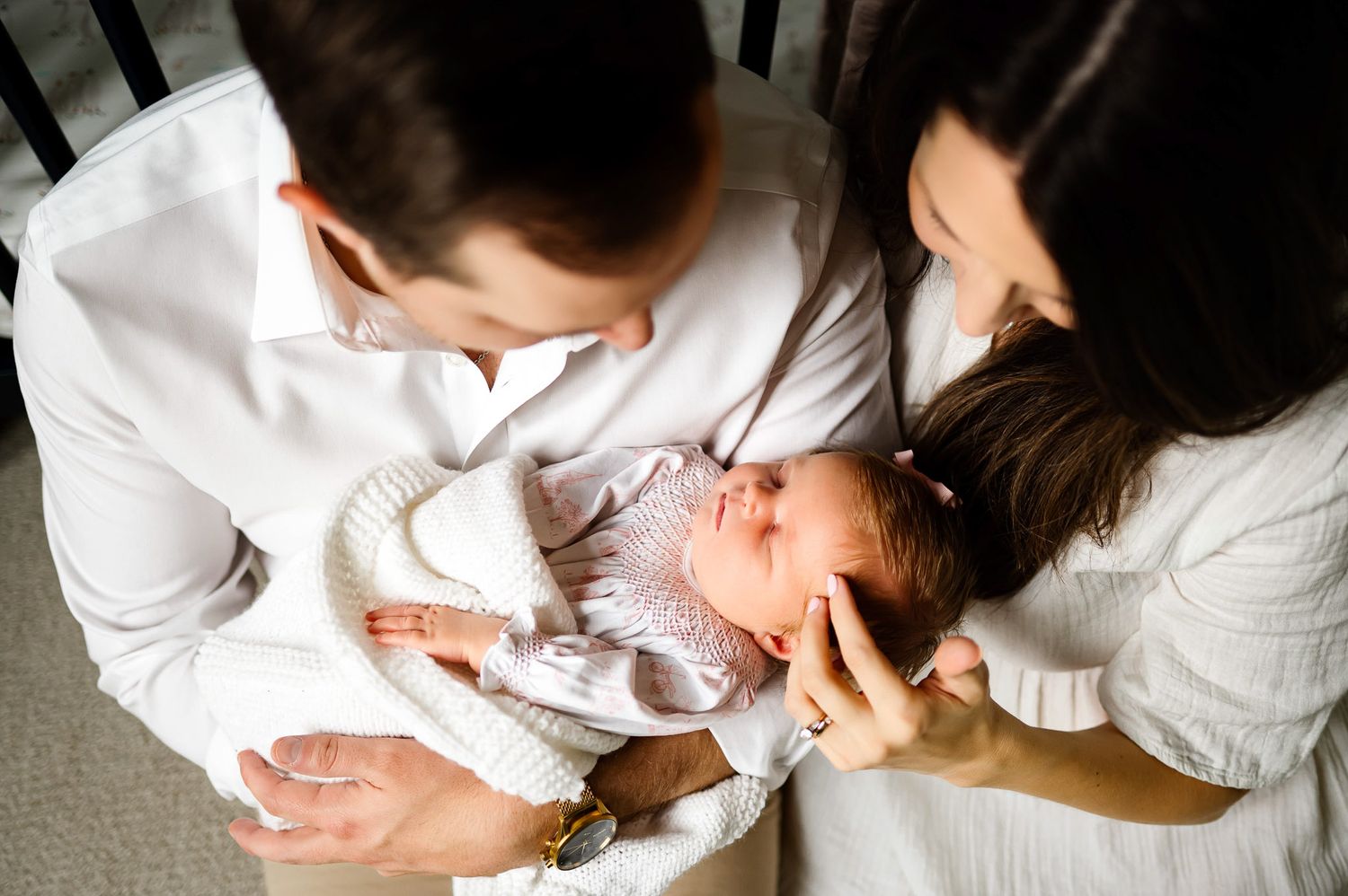 Parents looking down at their sleeping newborn baby during a natural light in-home newborn photography session in Raleigh