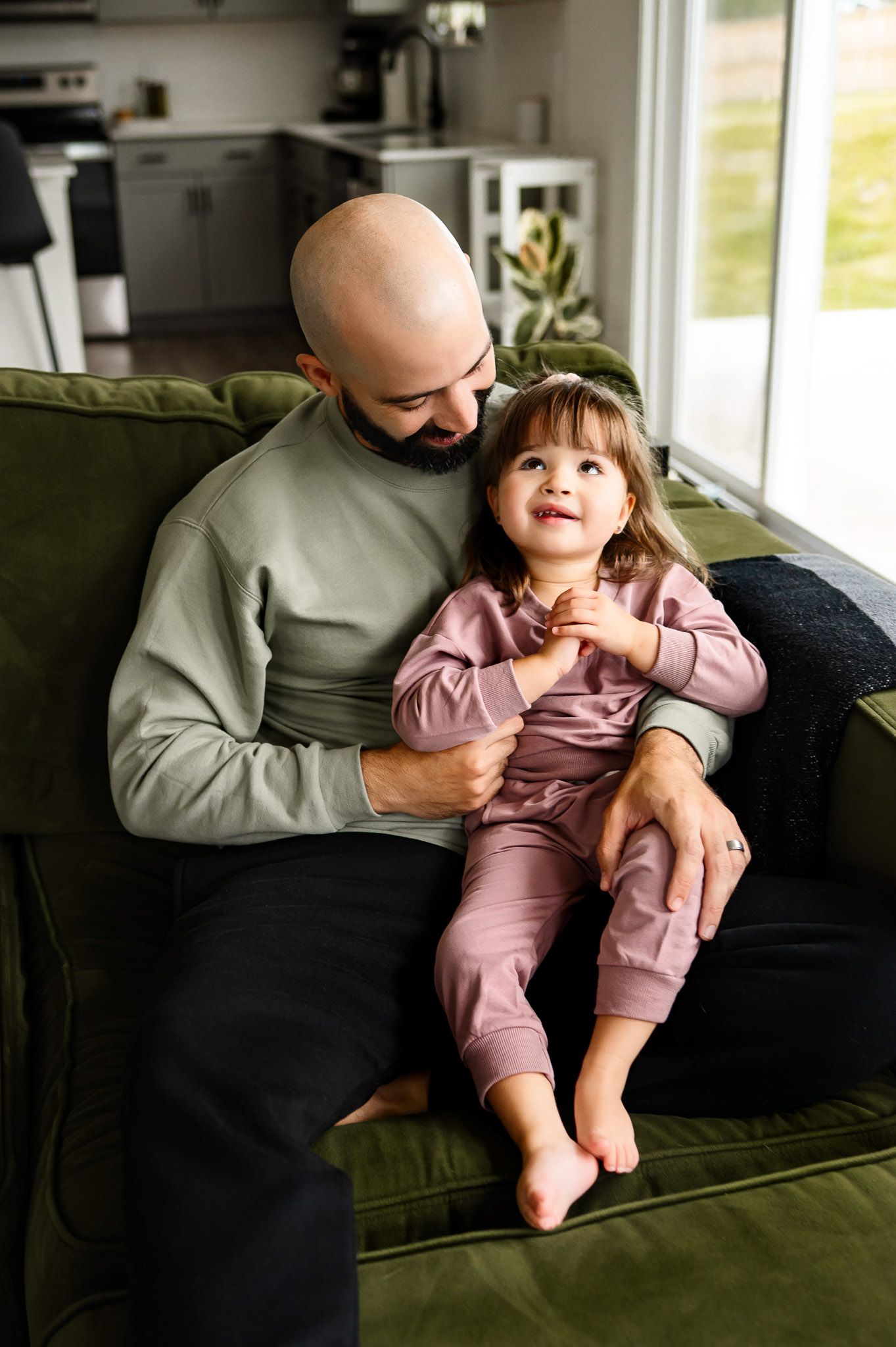 Father sitting with his daughter on a couch during a relaxed in-home family photography session in Raleigh North Carolina