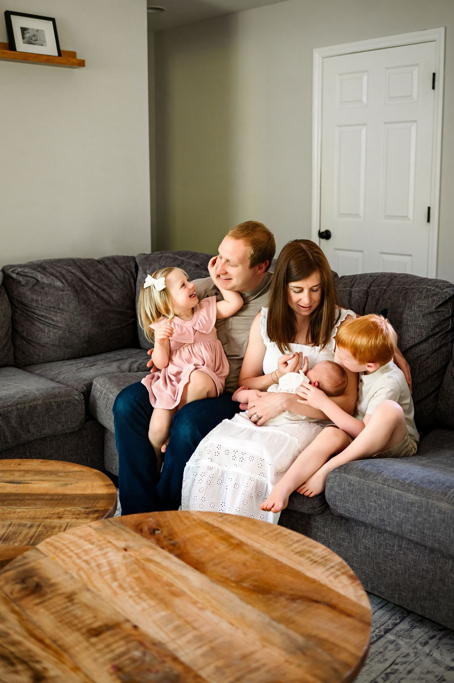 Family of five cuddling on a couch during an in-home lifestyle newborn photography session in Raleigh North Carolina