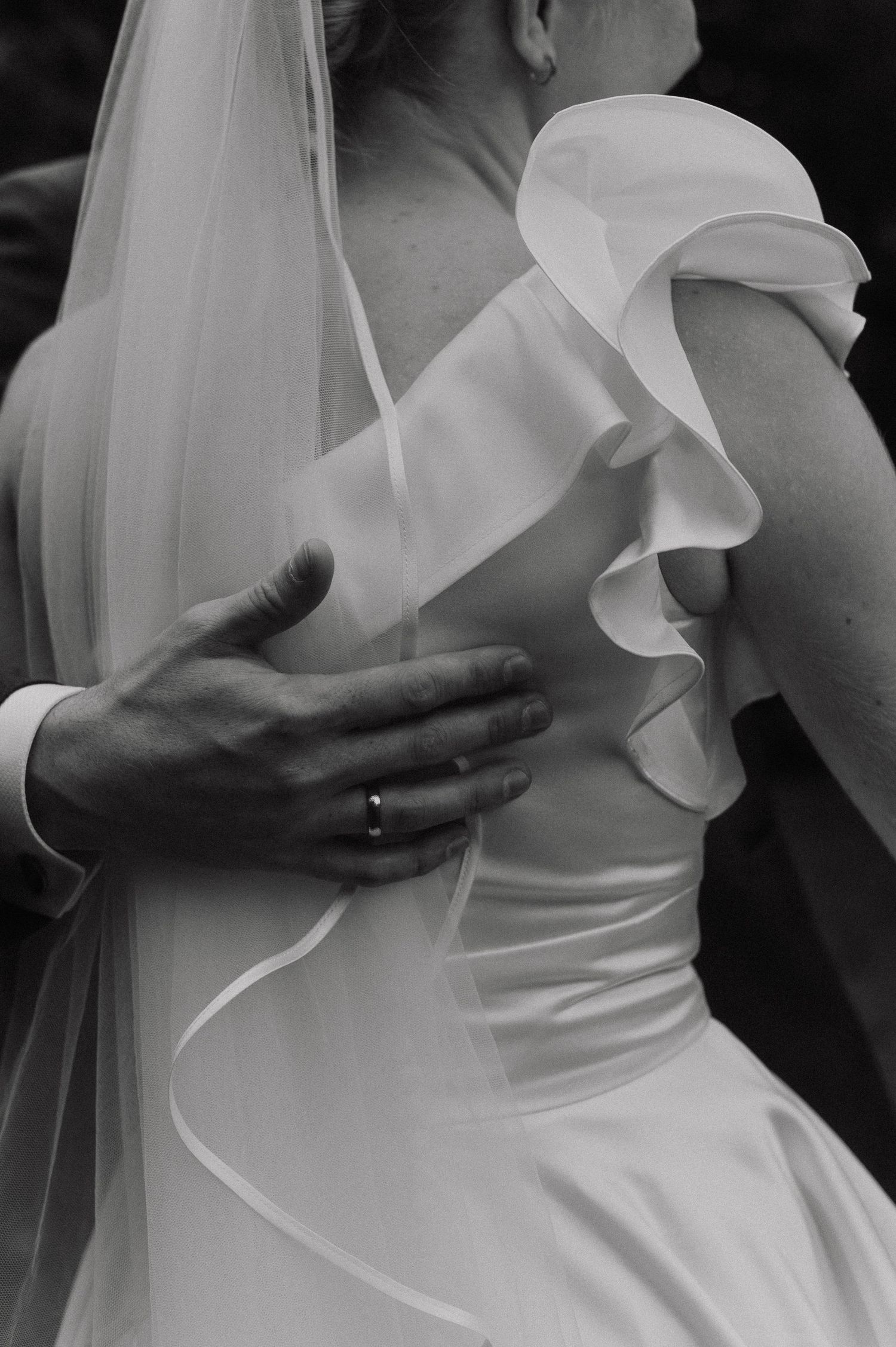 Close-up black and white details of a white wedding dress bodice with ruffled fabric.