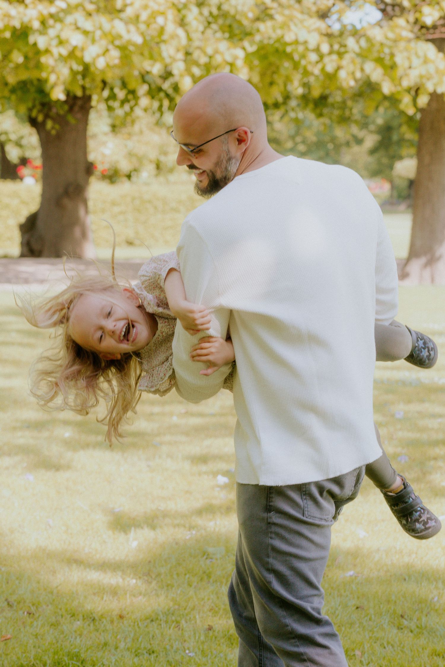 A playful sequence shows two people in white and grey clothing spinning and dancing together outdoors in a park setting.