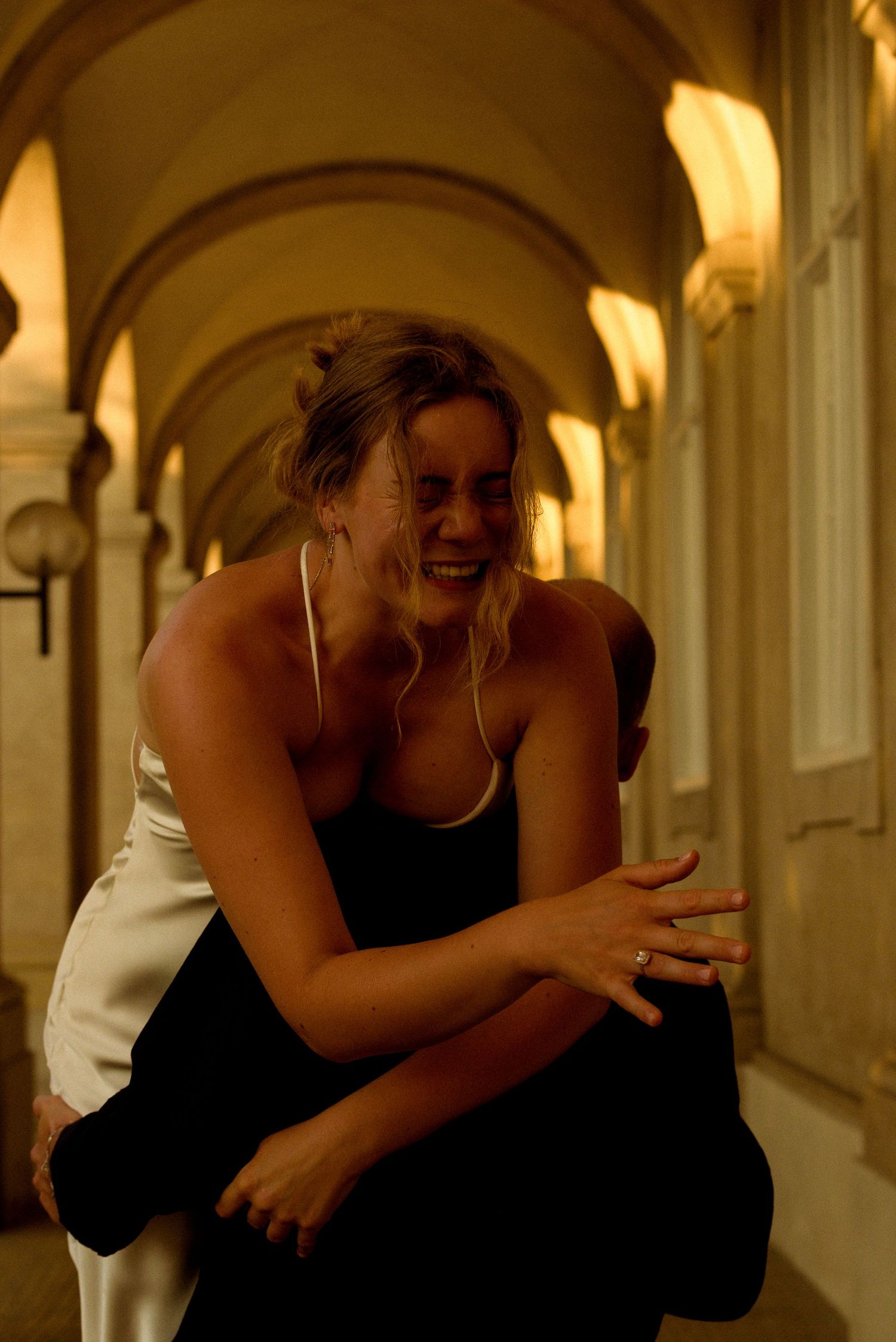 A joyful moment captured under arched hallways with warm lighting.