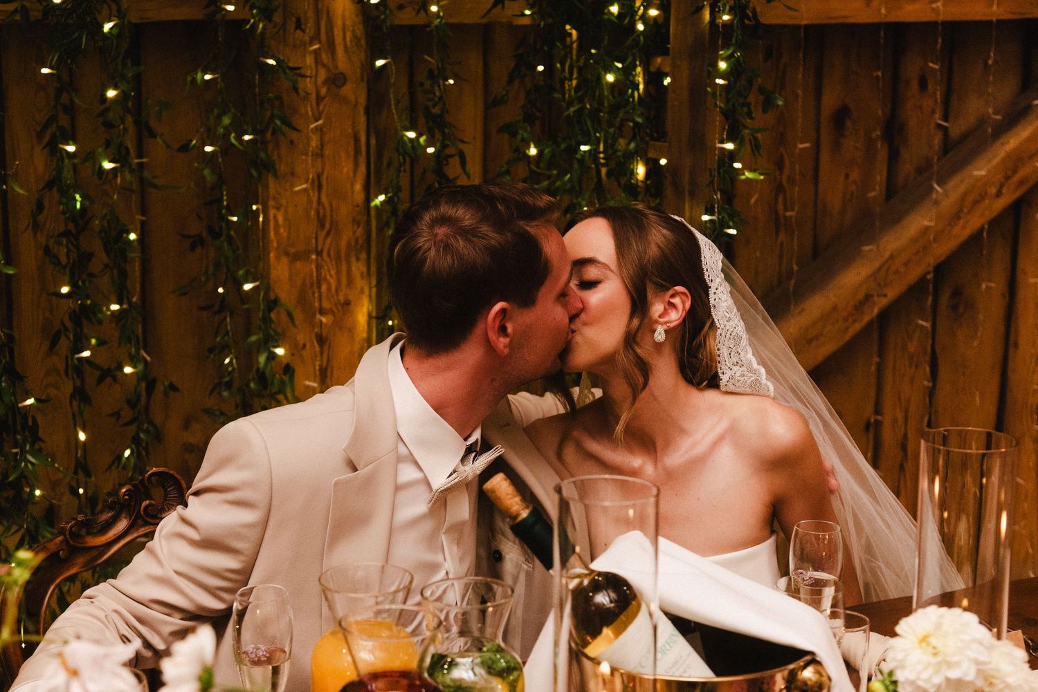 Romantic wedding couple shares intimate moments in a rustic barn setting with twinkle lights.