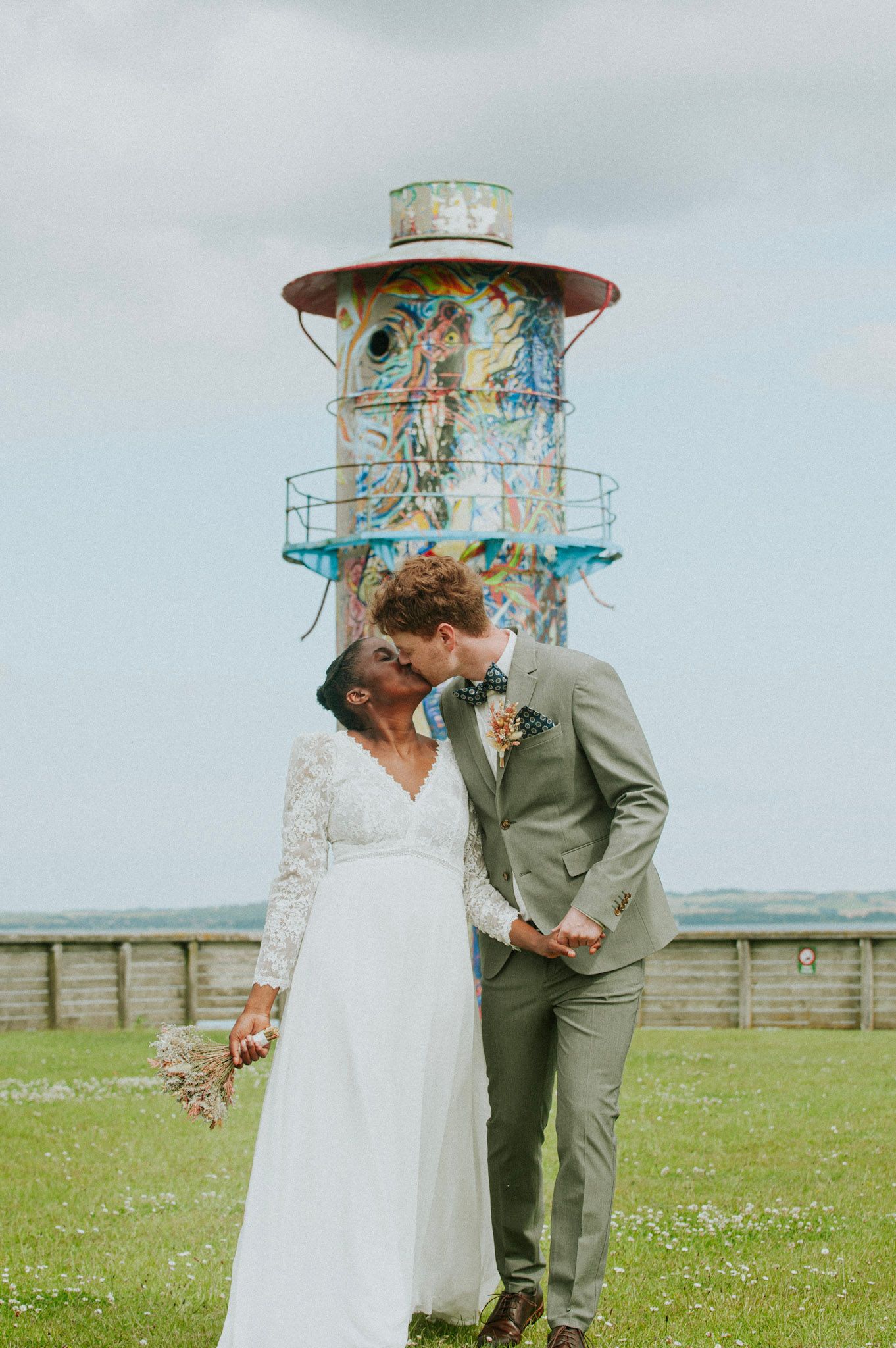 Romantic wedding portraits captured in a field with lighthouse in background.