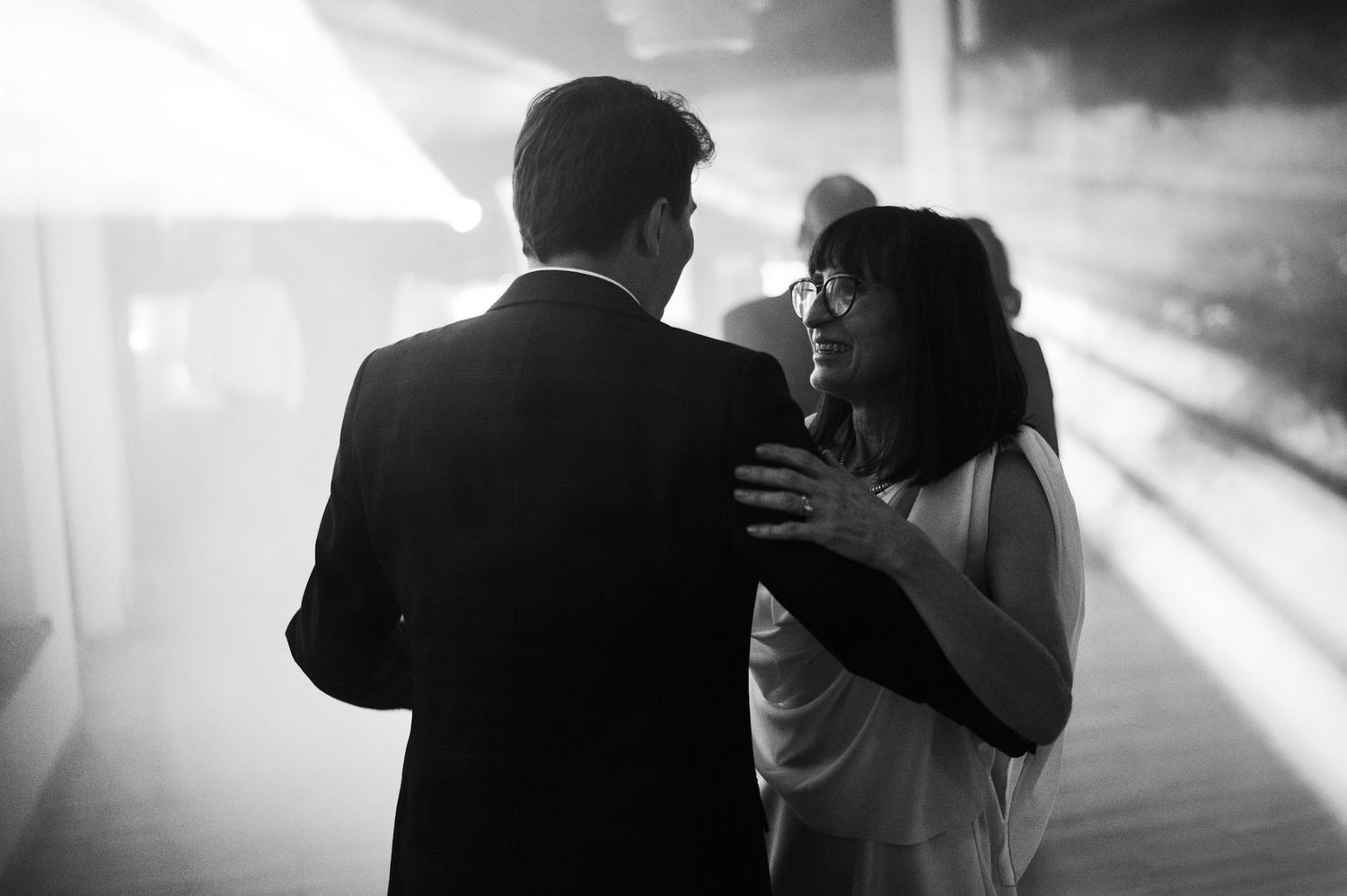 Silhouetted dancing figures captured in high contrast black and white during wedding reception.