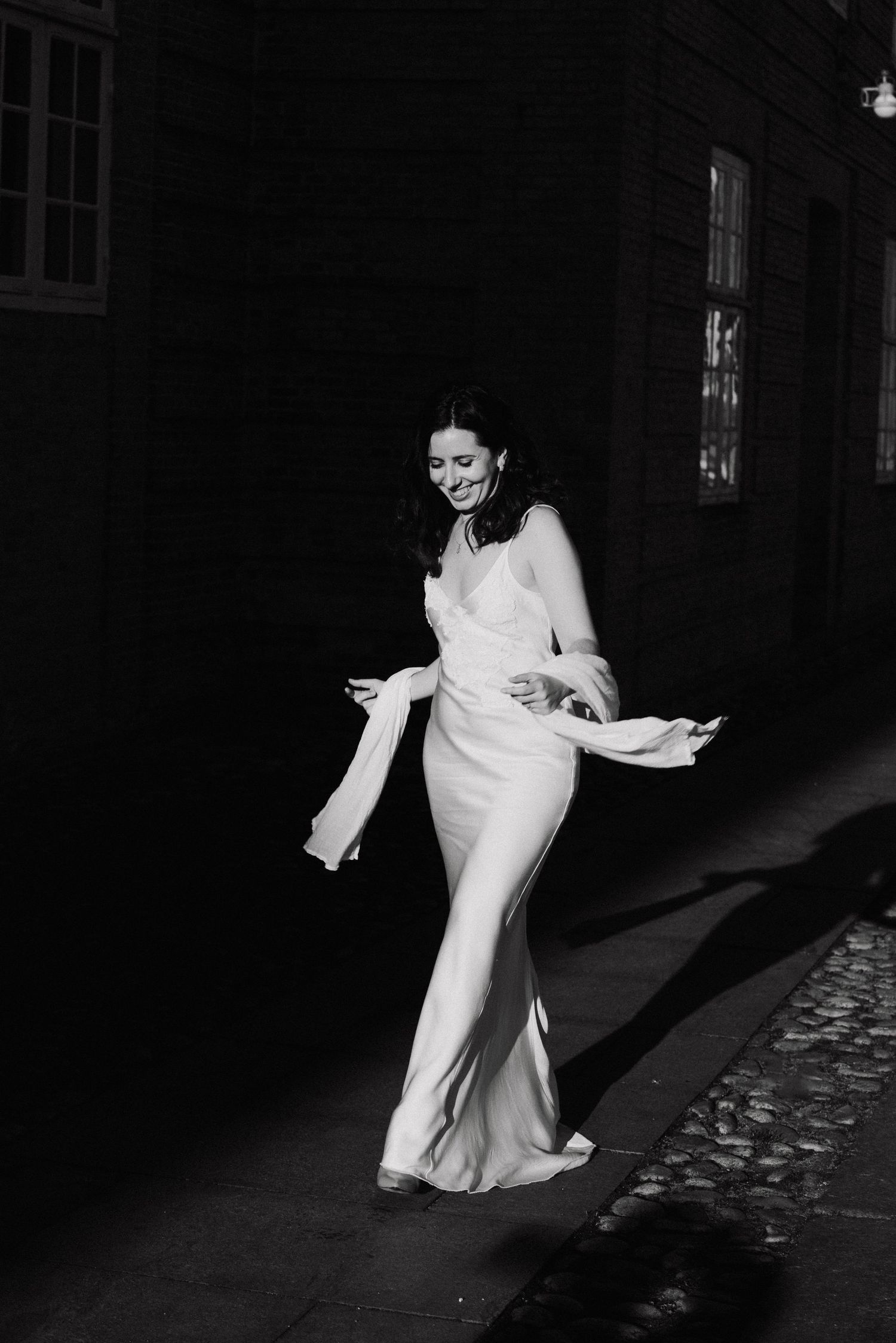 A sequence of black and white photos showing a bride twirling in her flowing white dress on a cobblestone street.