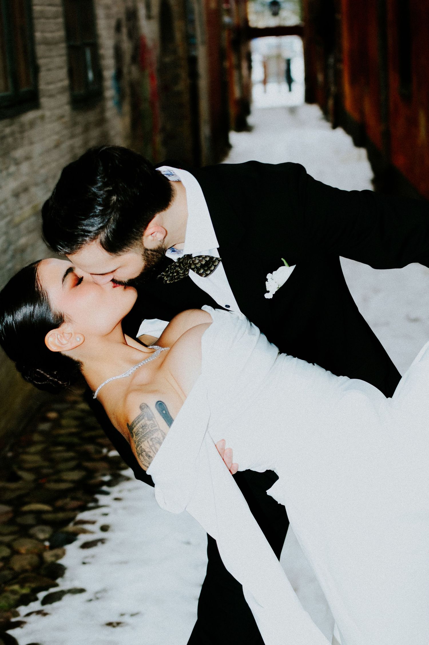 Dramatic dip kiss between newlyweds in classic black and white attire.