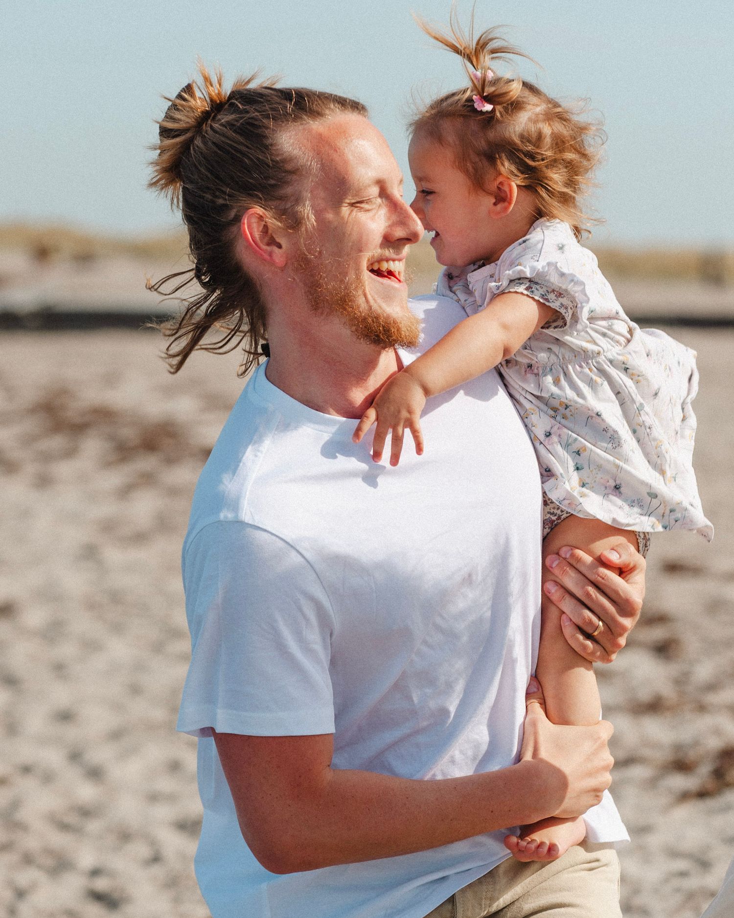 Tender family interactions shown in series of candid beach photos with soft lighting and white attire.