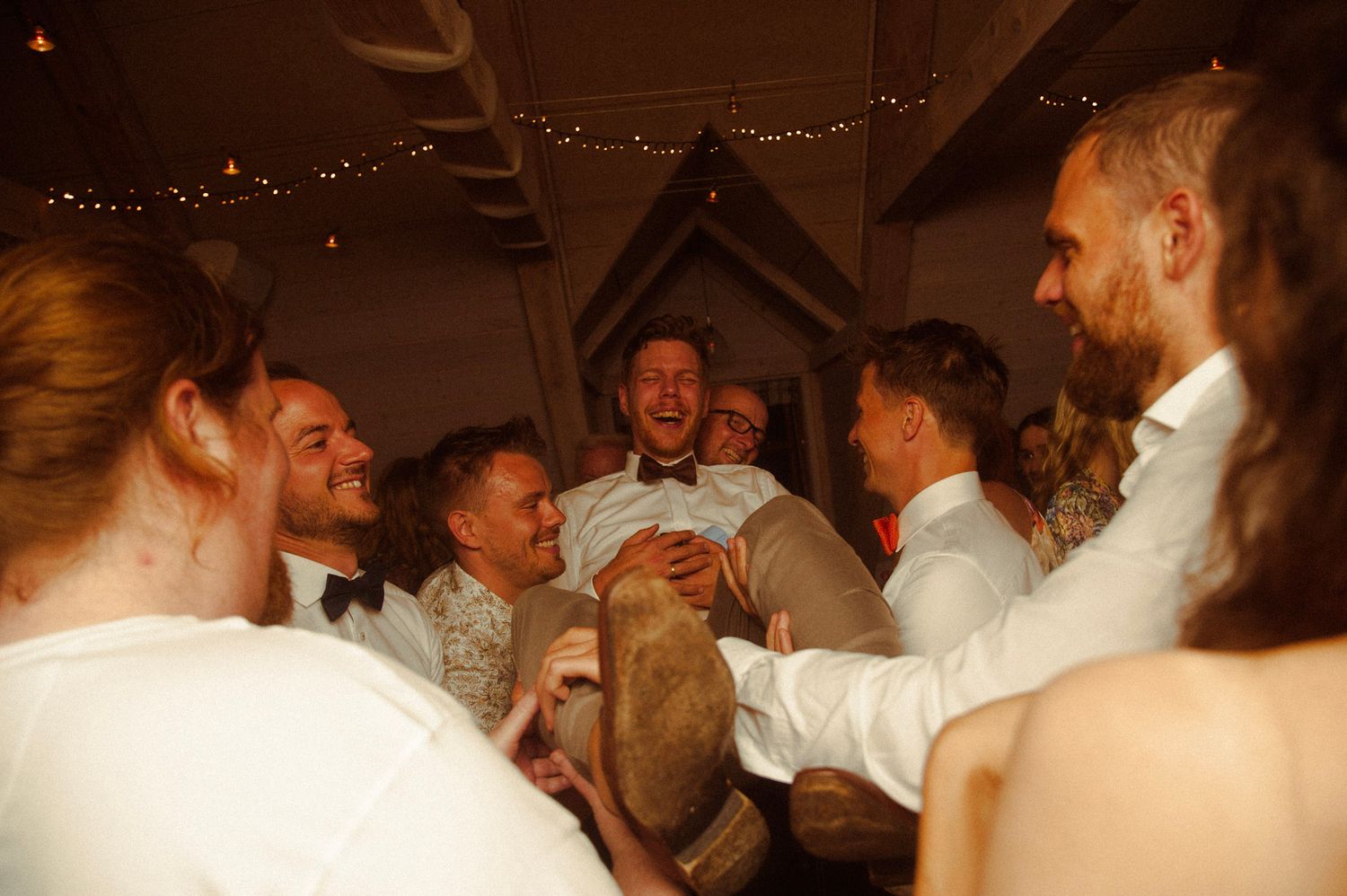 A lively crowd dancing and celebrating at an indoor wedding reception.