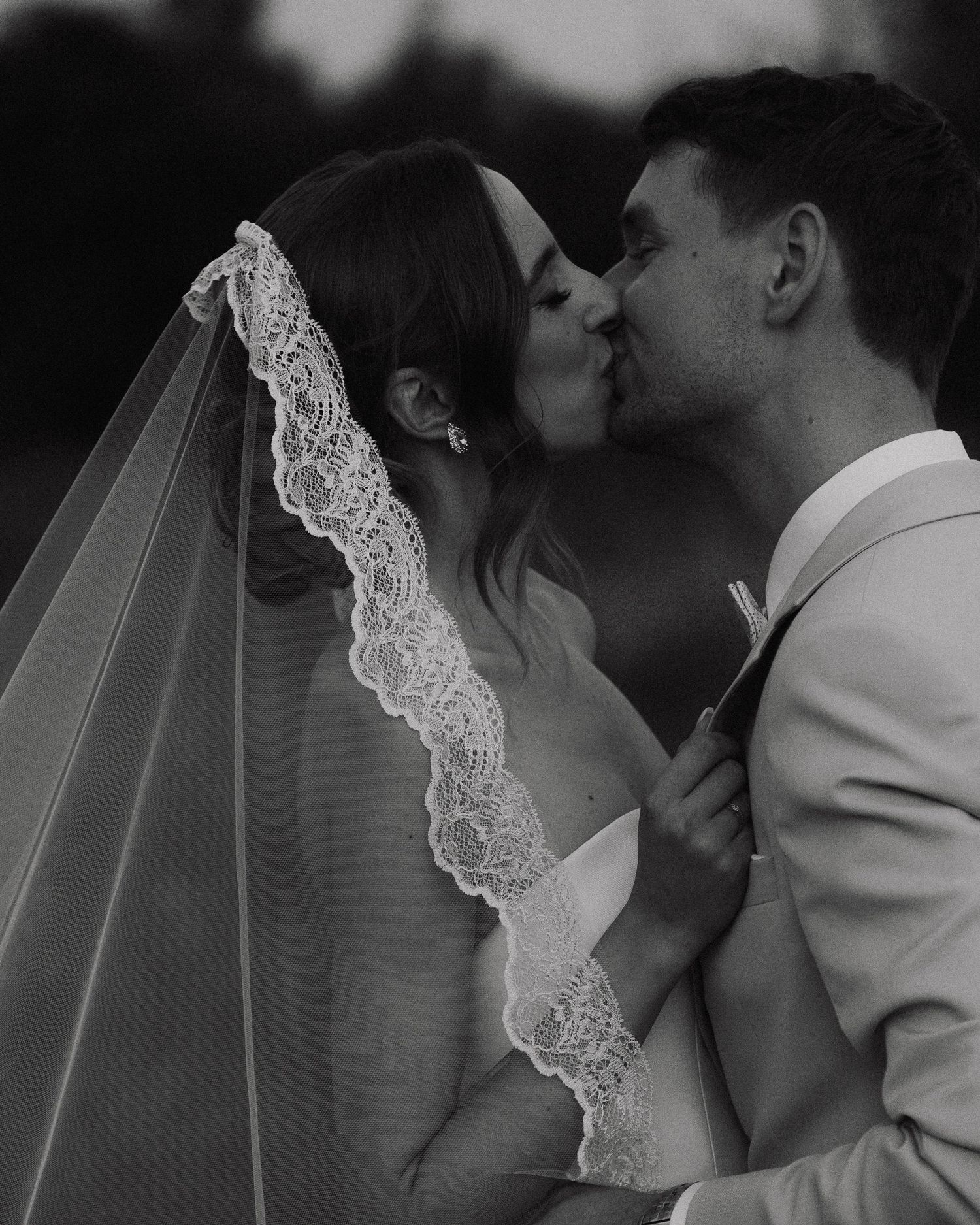 Black and white photo series of newlyweds sharing romantic kisses with bride wearing lace veil.
