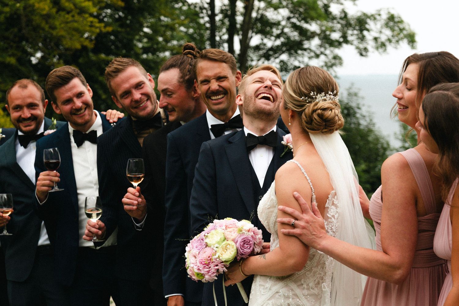 Wedding party members share laughter and joyful moments during outdoor celebration.
