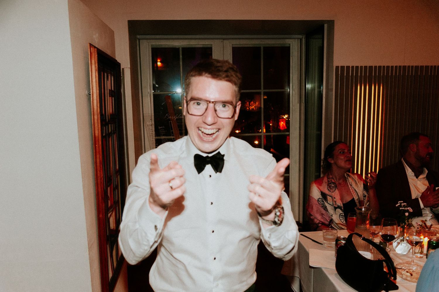 Wedding reception guests celebrate with dancing and joyful expressions indoors.