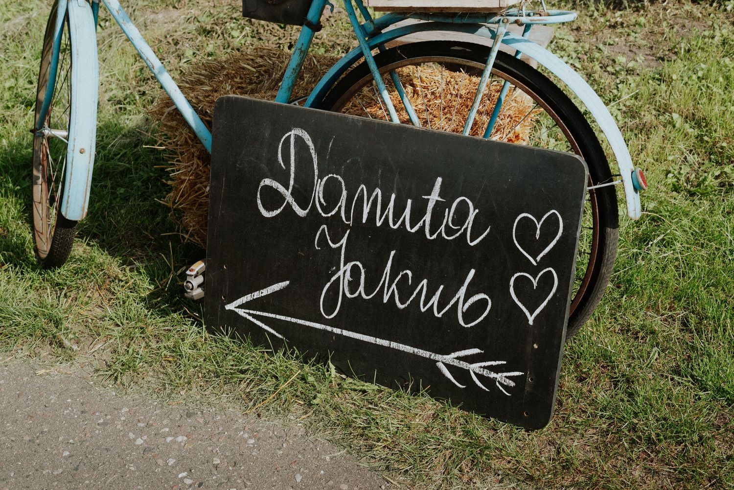 A vintage blue bicycle next to a black chalkboard sign with handwritten text and heart drawings.