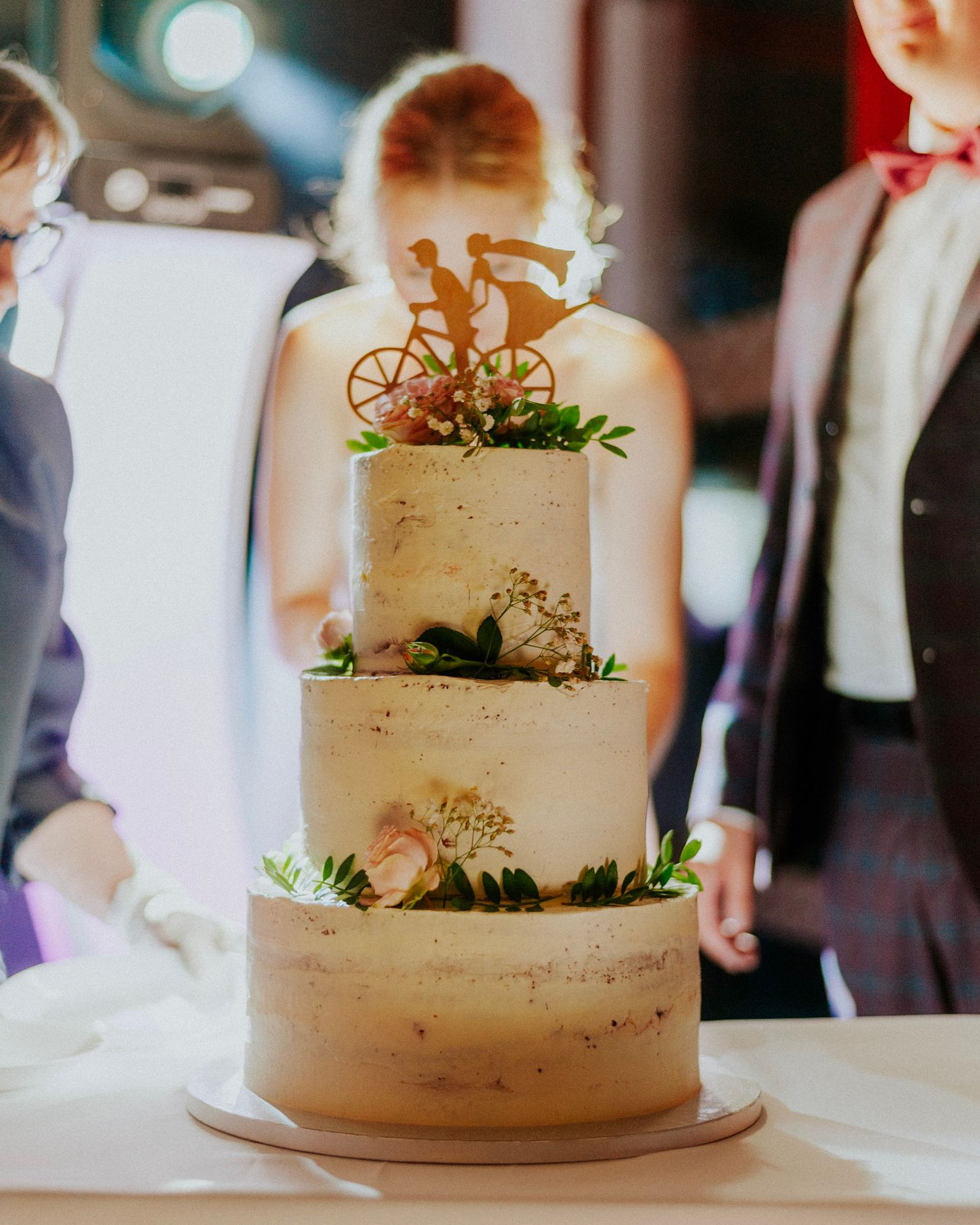 Elegant white wedding cake with delicate floral decorations and greenery accents.