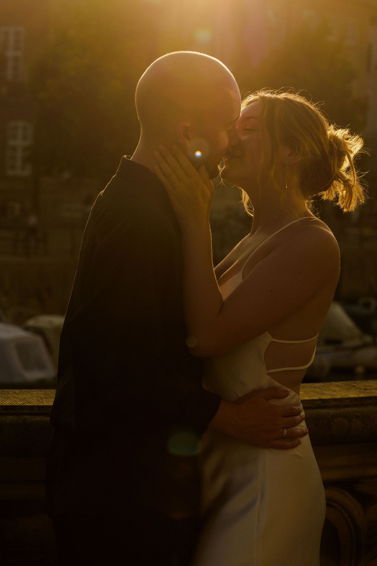A couple embraces in golden sunset light creating romantic silhouettes against a warm glowing background.