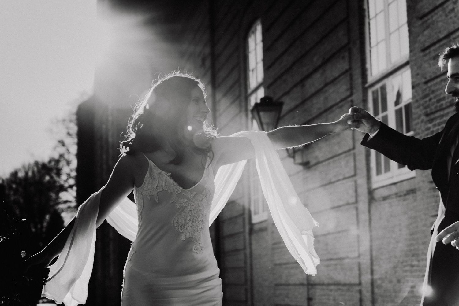 Black and white photo of a couple in wedding attire dancing together during a celebration.