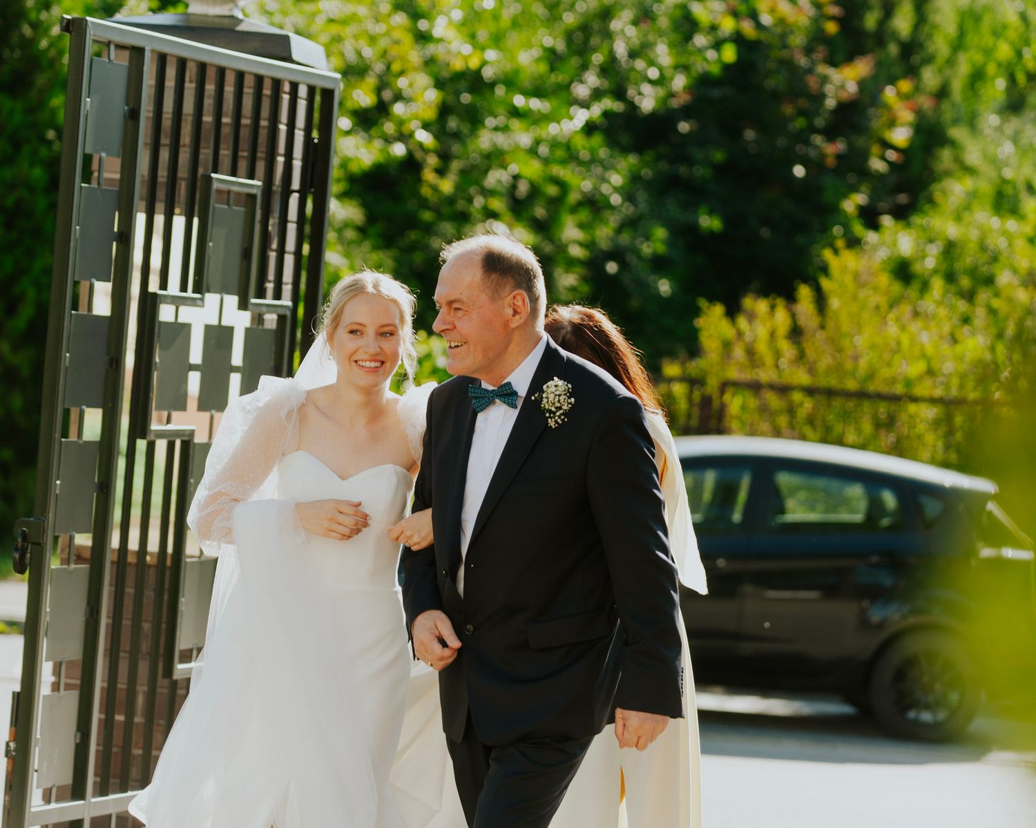 A joyful wedding couple walks together on a sunny day.