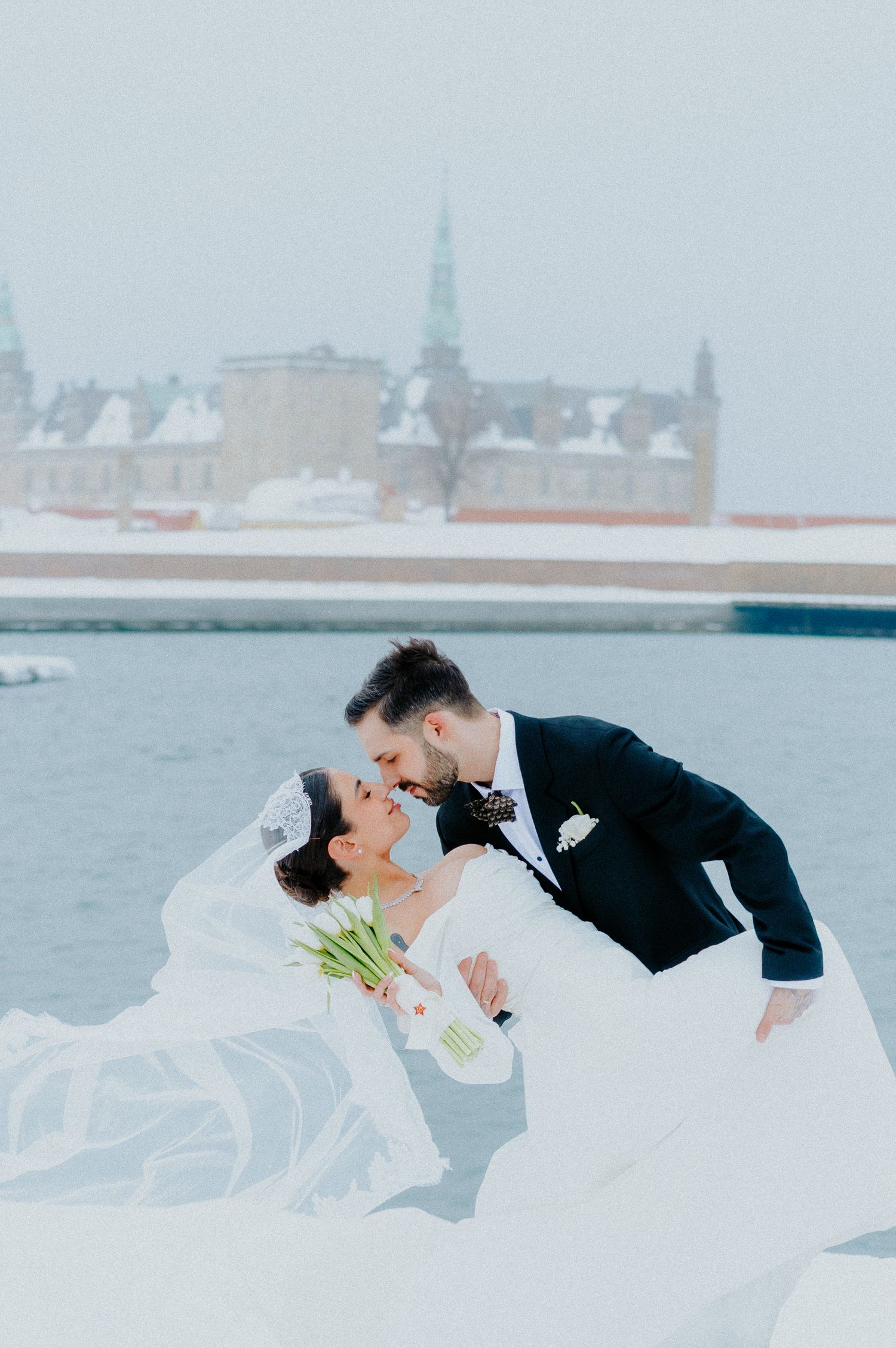 Romantic waterfront wedding photo with cityscape in background.