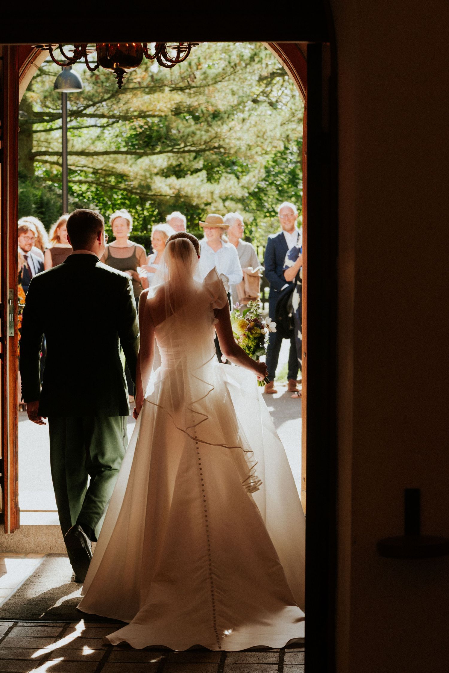 Elegant wedding scene silhouetted in a doorway with natural light streaming through.