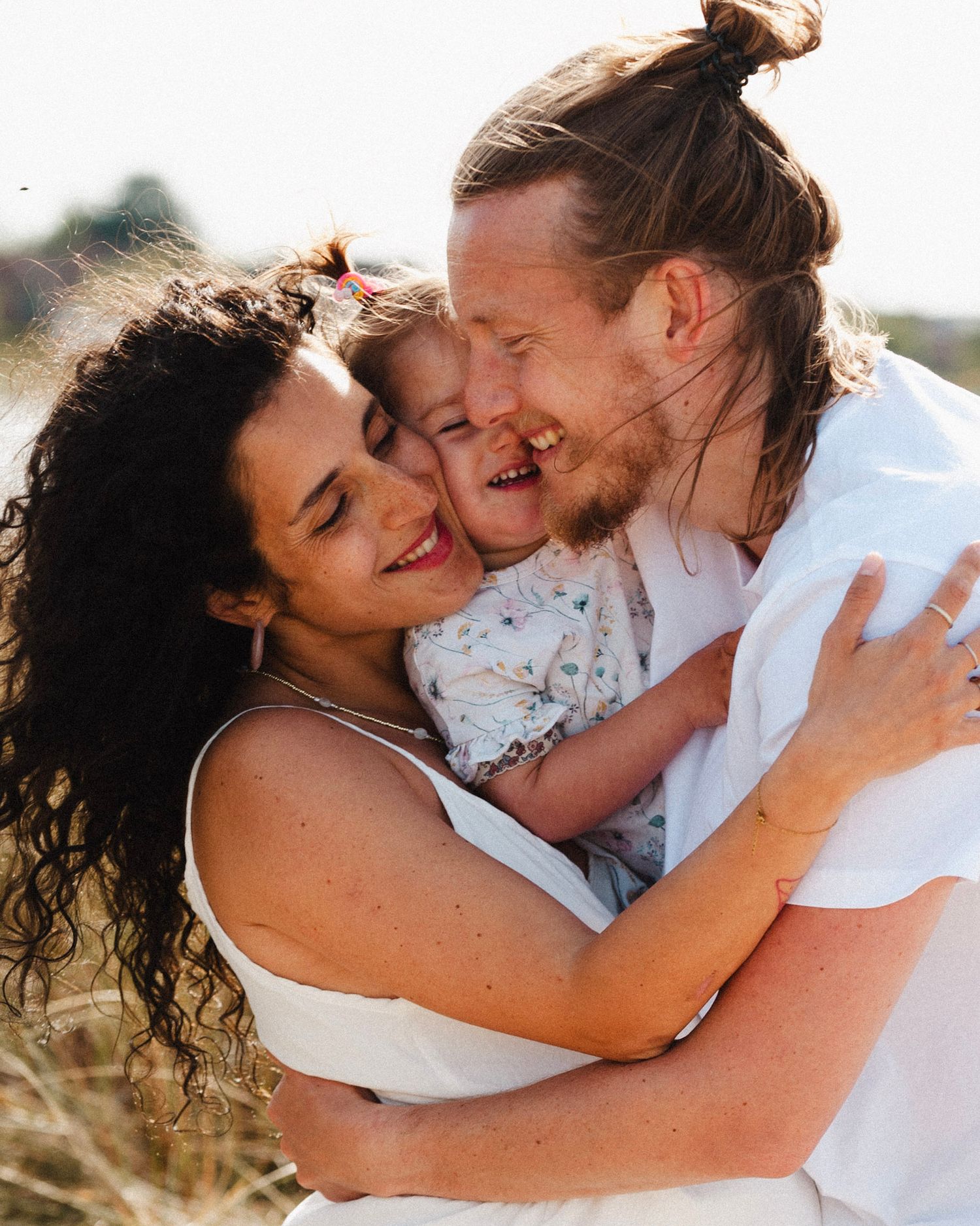 A joyful family sharing a warm embrace outdoors during golden hour in a candid moment of connection and love.