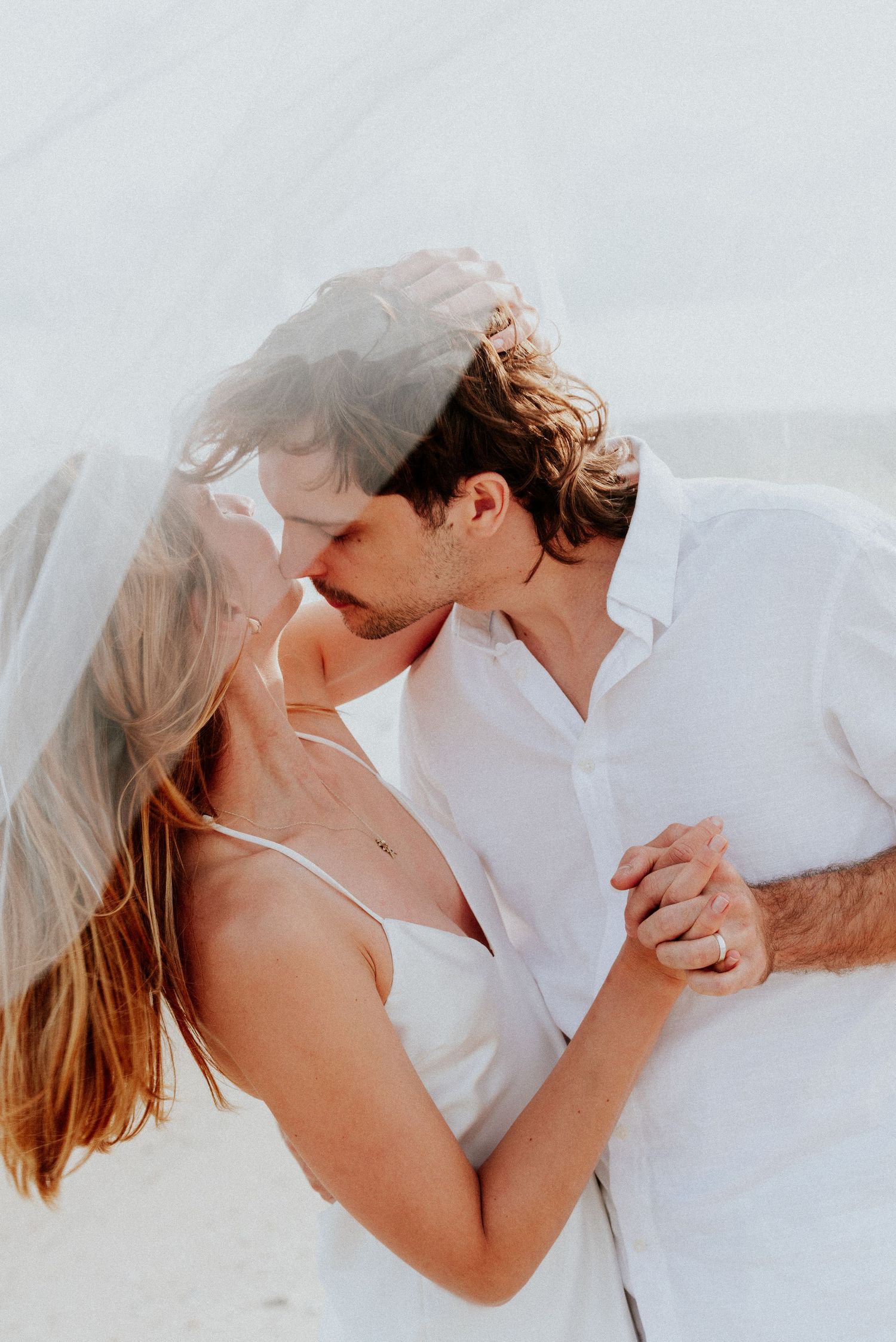 Romantic sequence of couple in white clothing embracing and sharing intimate moments on white background.