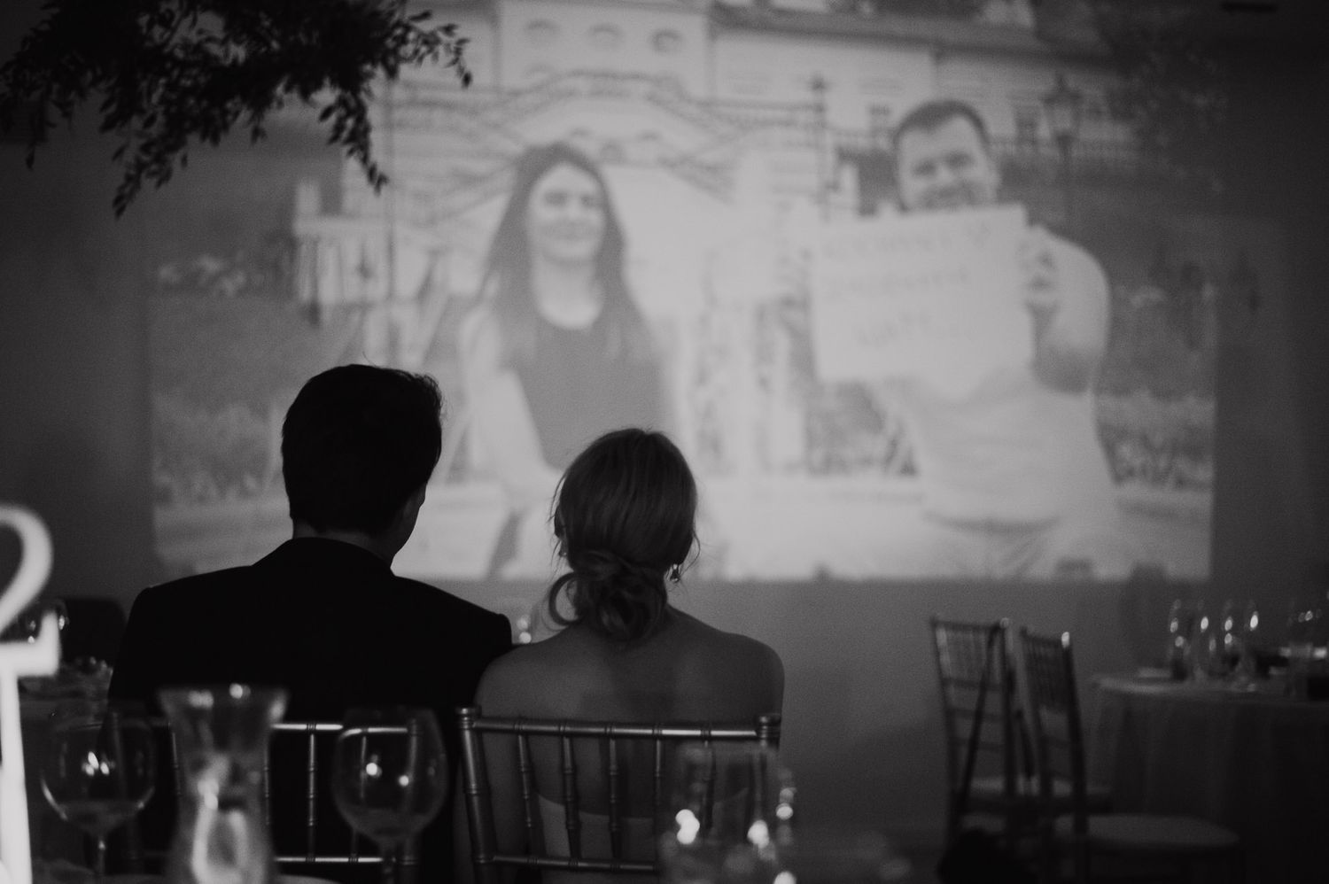 Wedding reception slideshow projection with guests silhouetted in foreground.