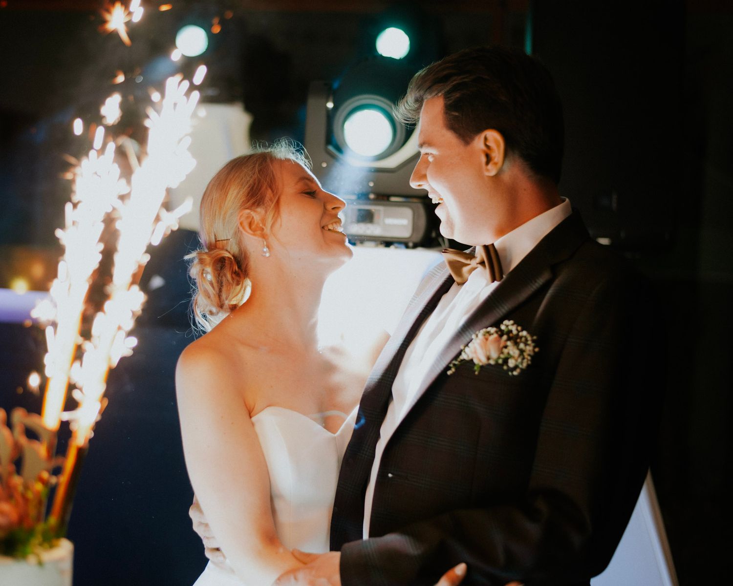 Wedding couple dancing amid dramatic lighting and special effects at evening reception.